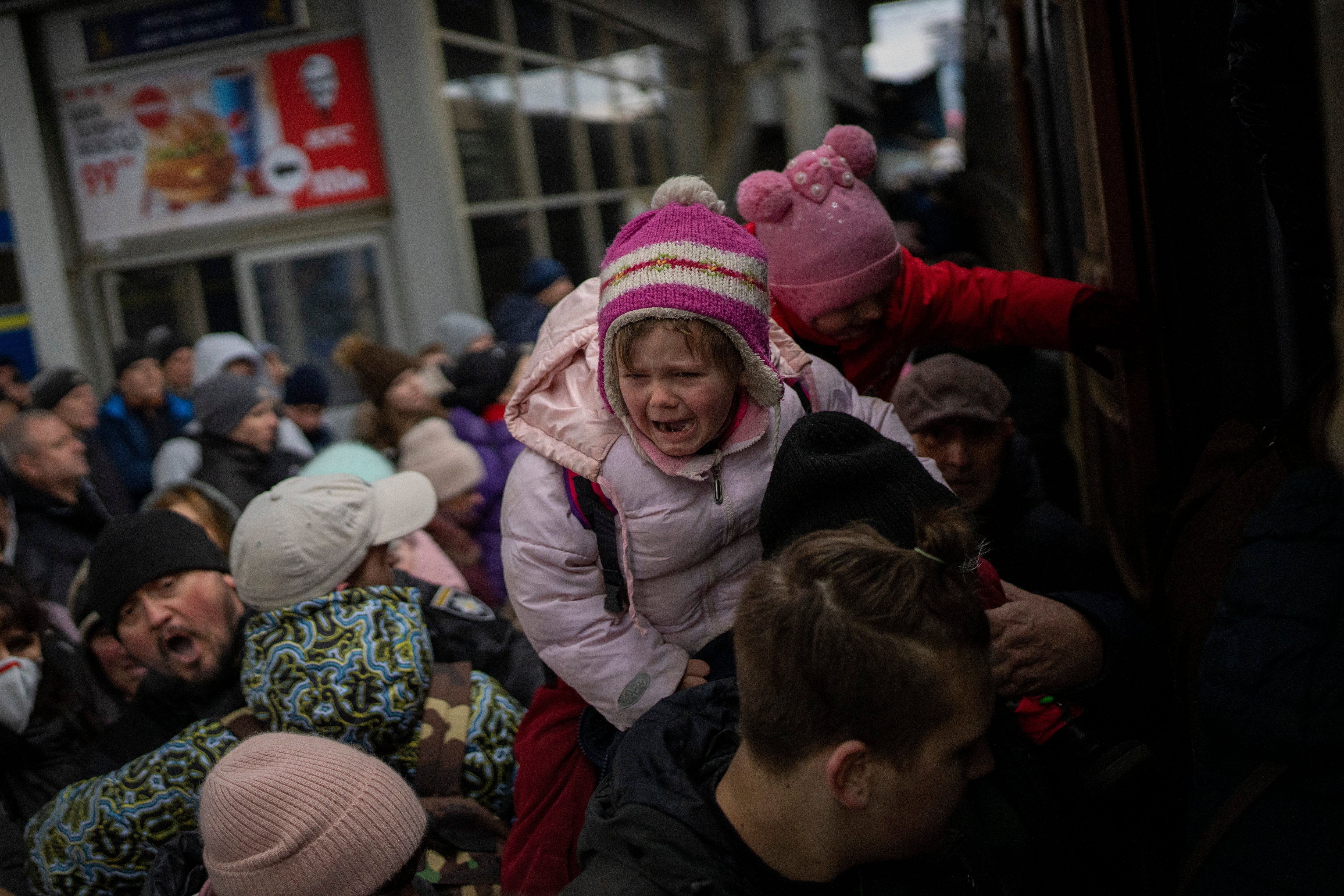People holding their children struggle to get on a train to Lviv at the Kyiv station.