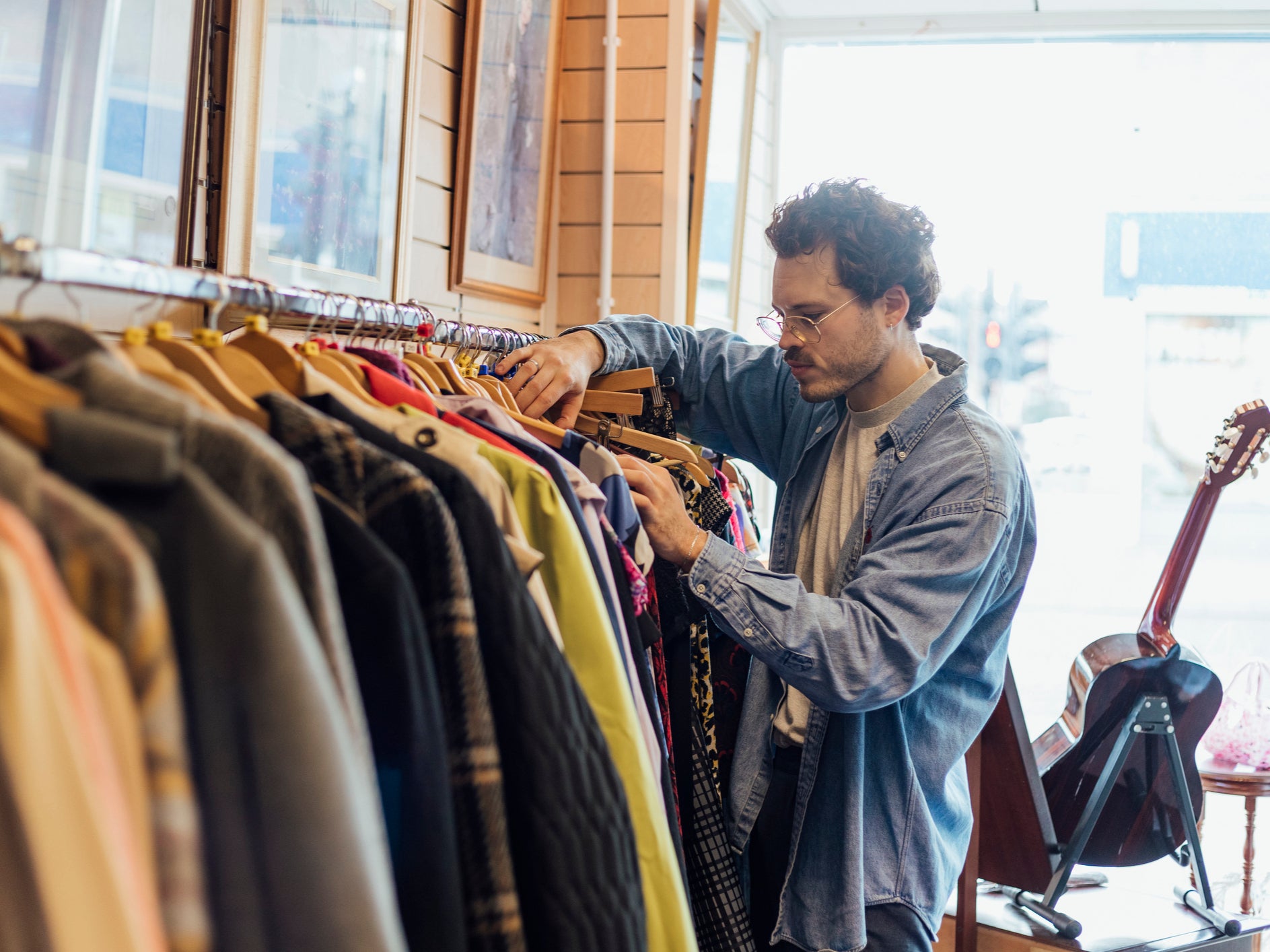 A man looking through second hand clothes at a charity shop in Newcastle-upon-Tyne. According to academics people should limit themselves to buying three new items of clothing a year