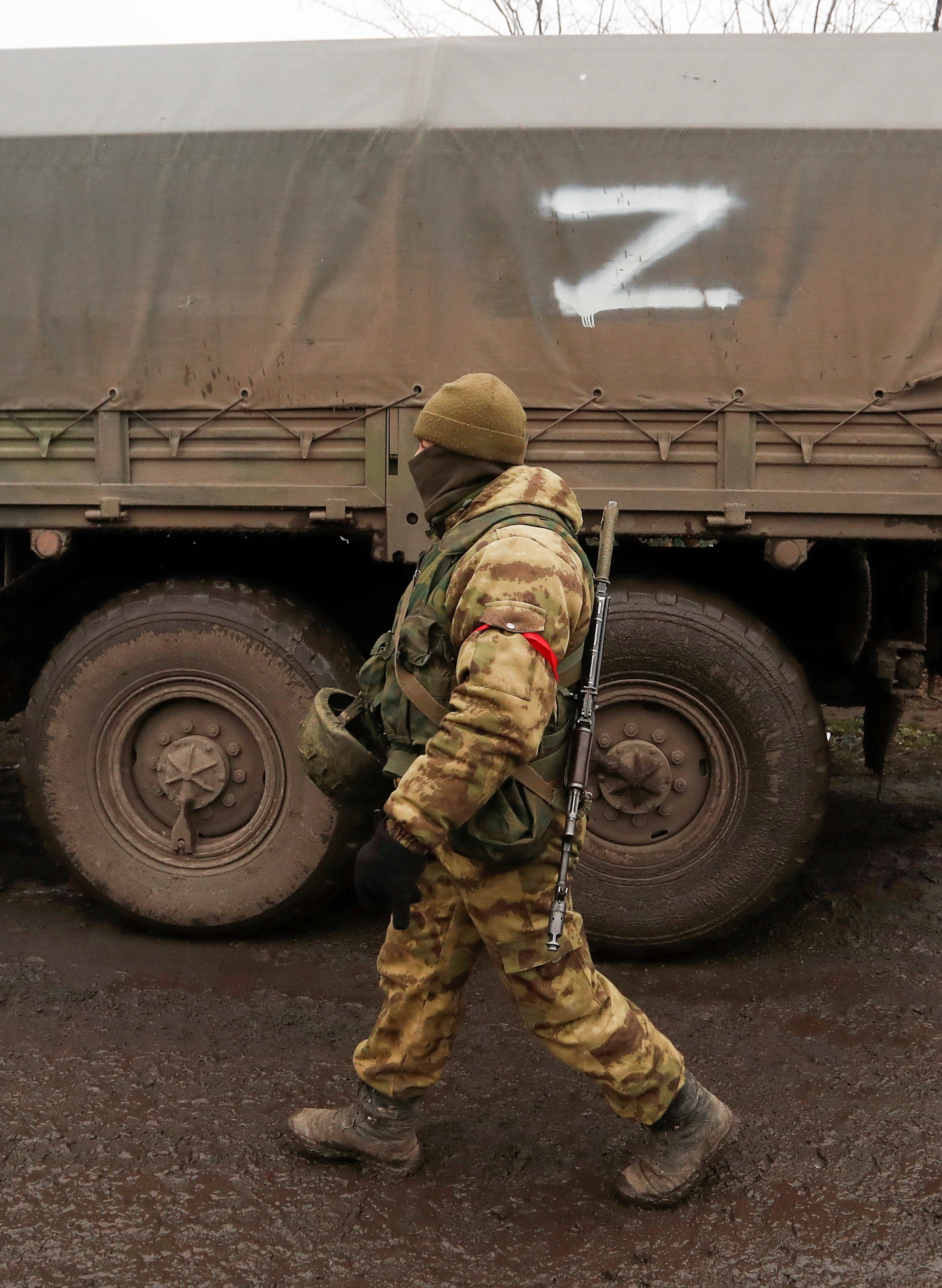 A service member of pro-Russian troops in a uniform without insignia walks past a truck with the symbol "Z" painted on its side in the separatist-controlled settlement of Rybinskoye during Ukraine-Russia conflict in the Donetsk region, Ukraine, on 5 March