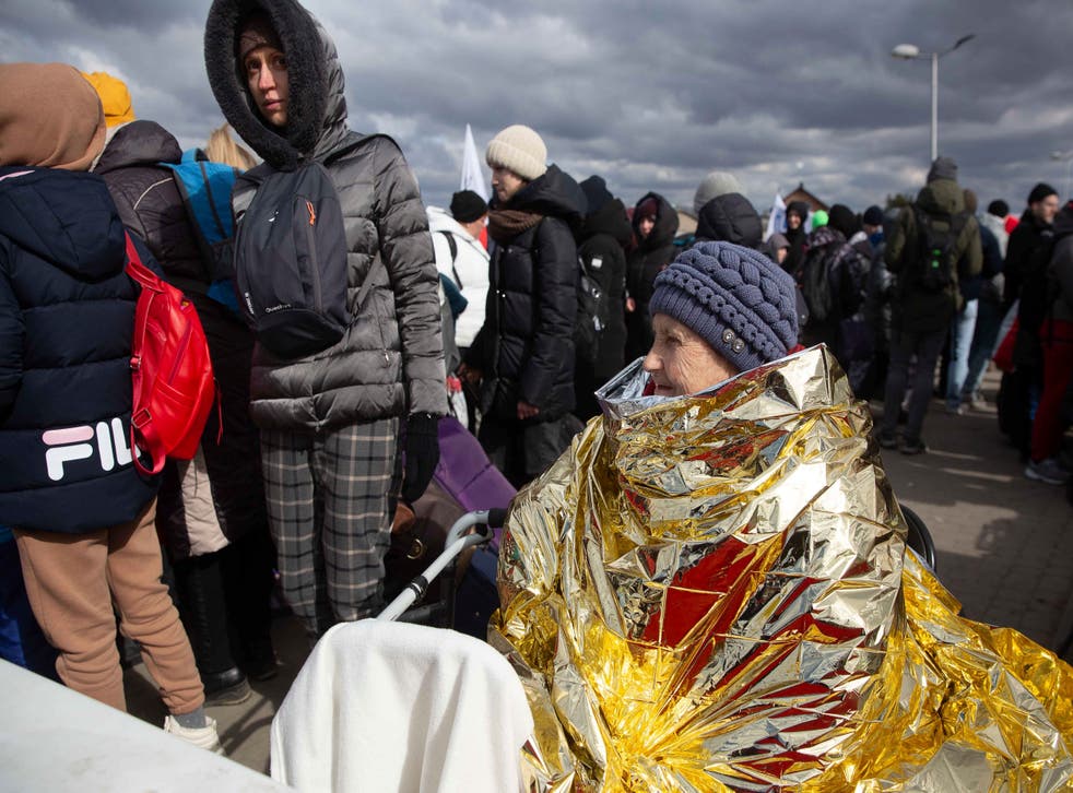 A woman wrapped in thermal blanket fleeing from Ukraine, waits to board a bus at the border crossing in Medyka, Poland (Visar Kryeziu/AP/PA)