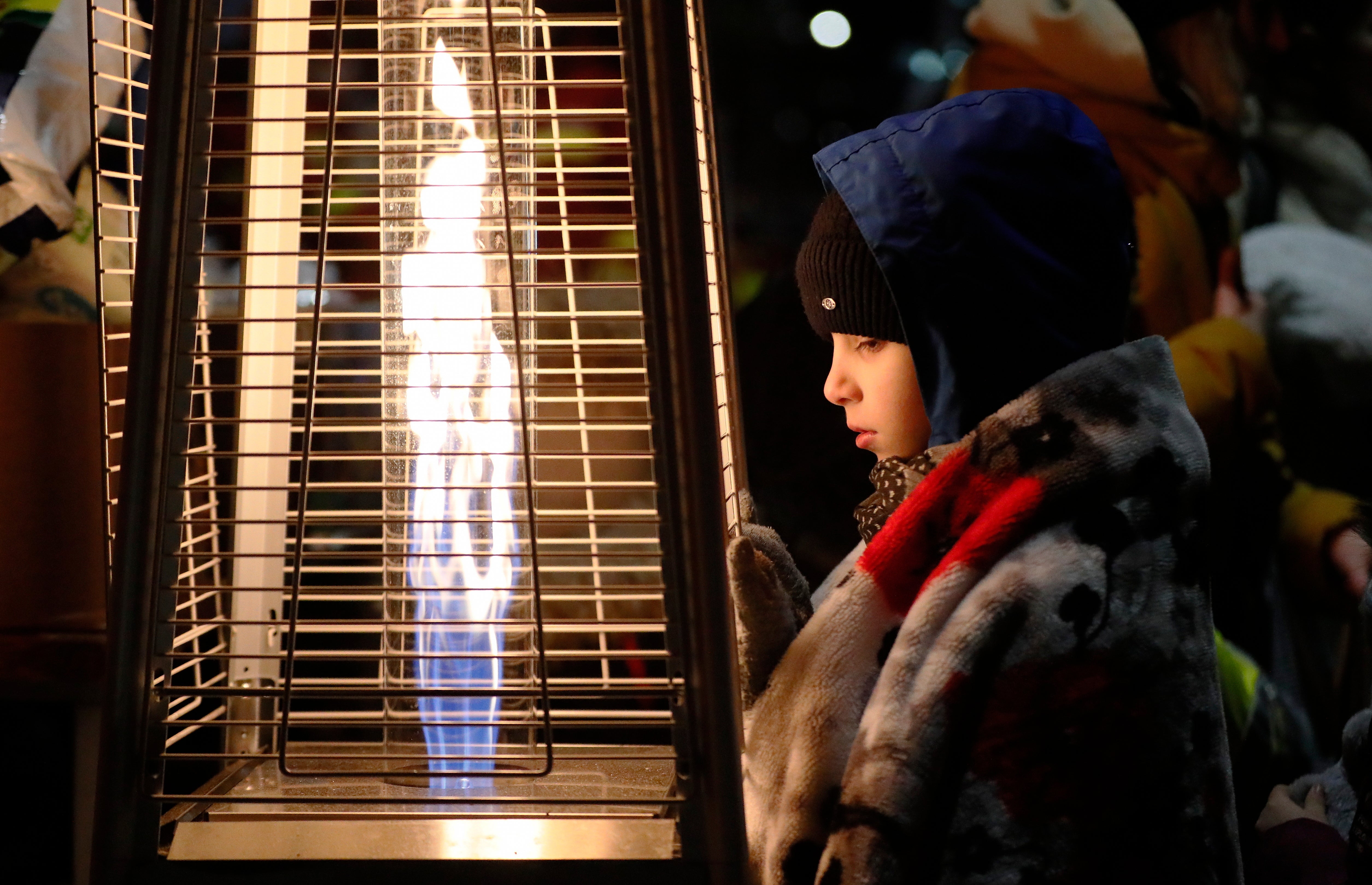 A Ukrainian boy warms up beside a gas heater, shortly after passing through the border crossing of Siret, northern Romania