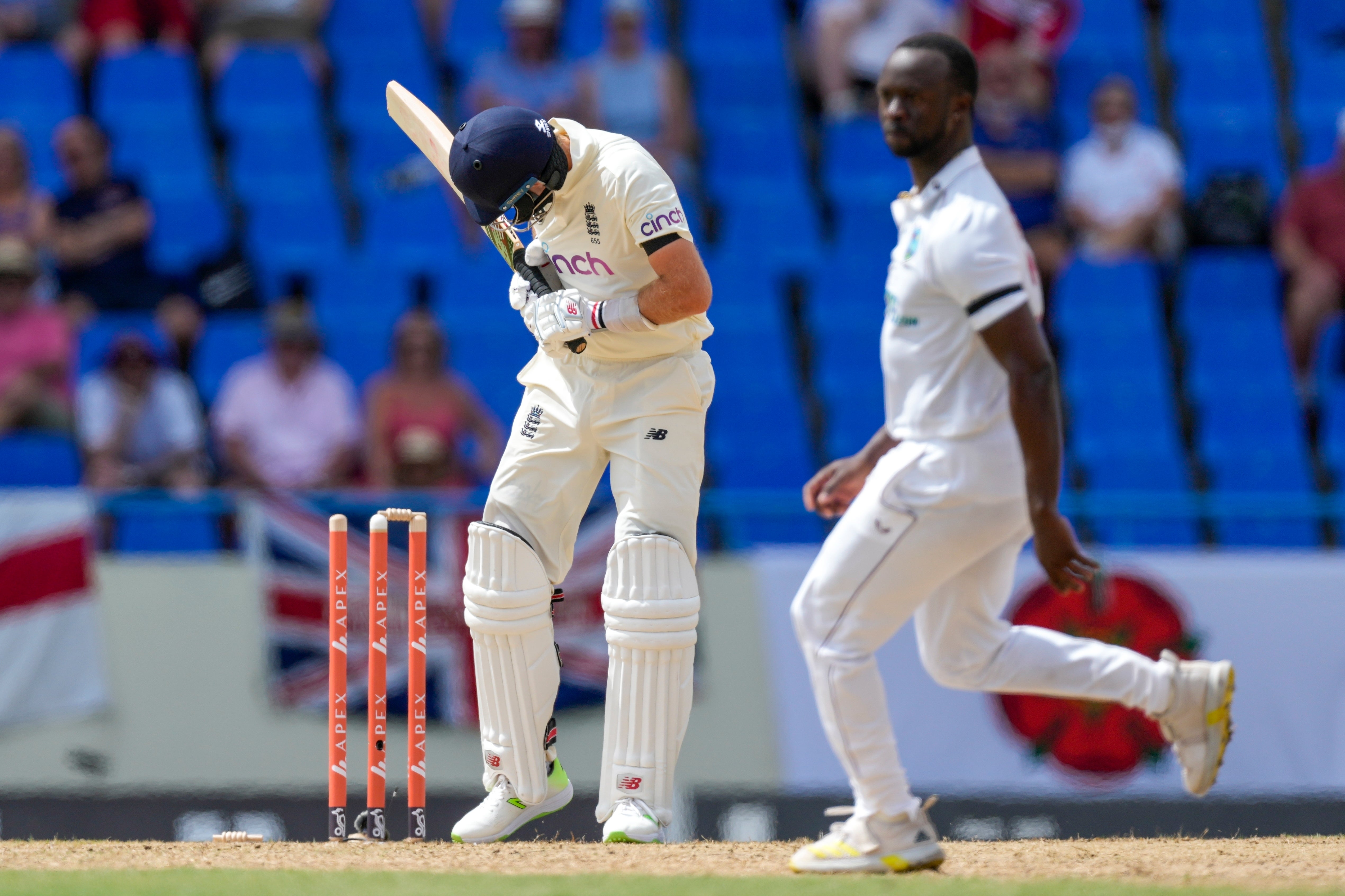 Joe Root checks his broken wicket as West Indies paceman Kemar Roach, right, soaks up the applause (Ricardo Mazalan/AP)