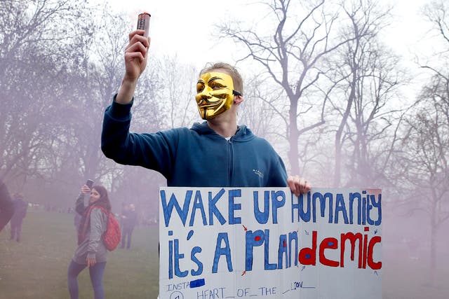 <p>A protester carrying a placard claiming Covid is a hoax at a rally in London in March last year </p>