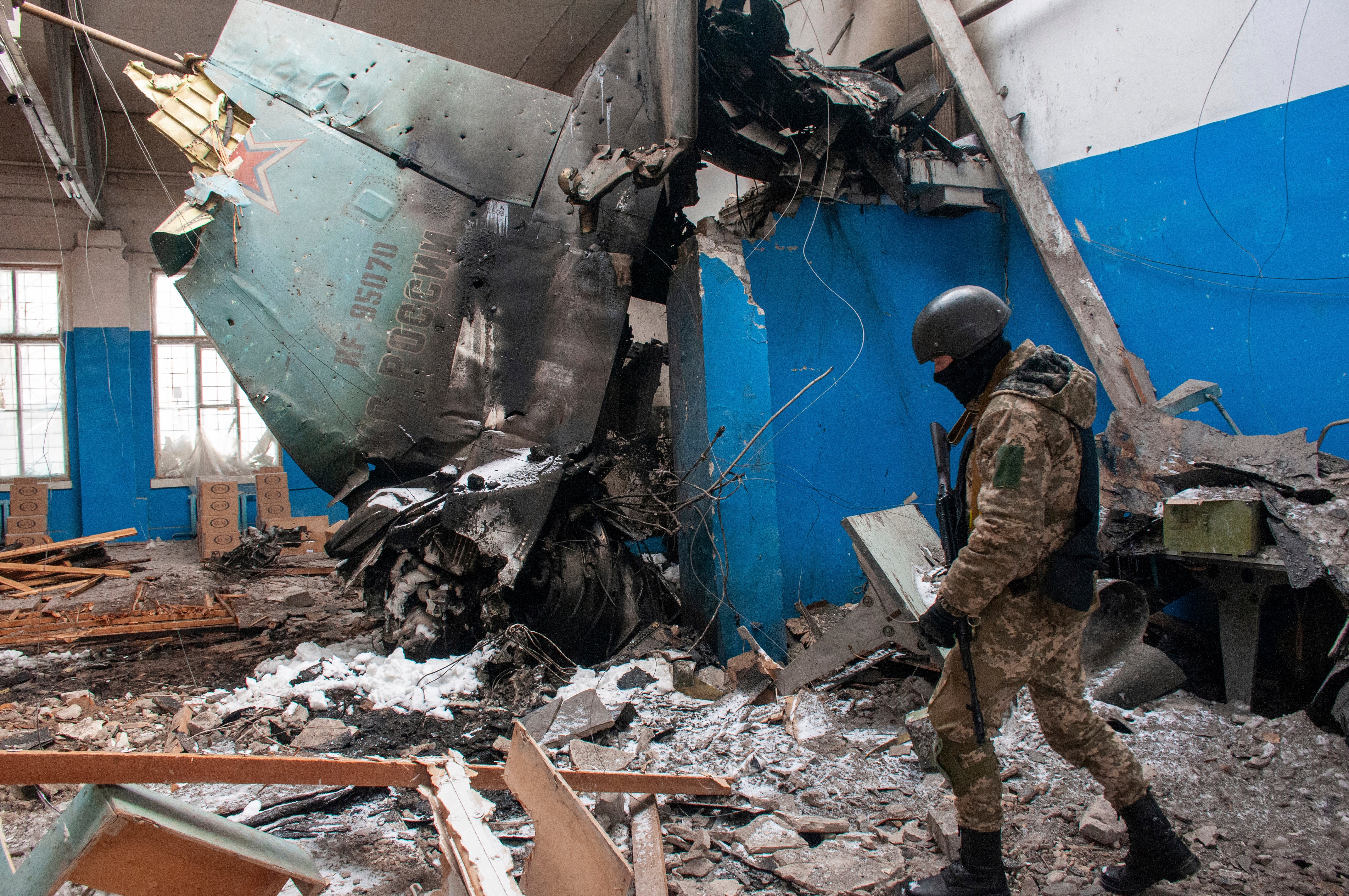 A Ukrainian serviceman walks past the vertical tail fin of a Russian Su-34 bomber lying in a damaged building in Kharkiv.