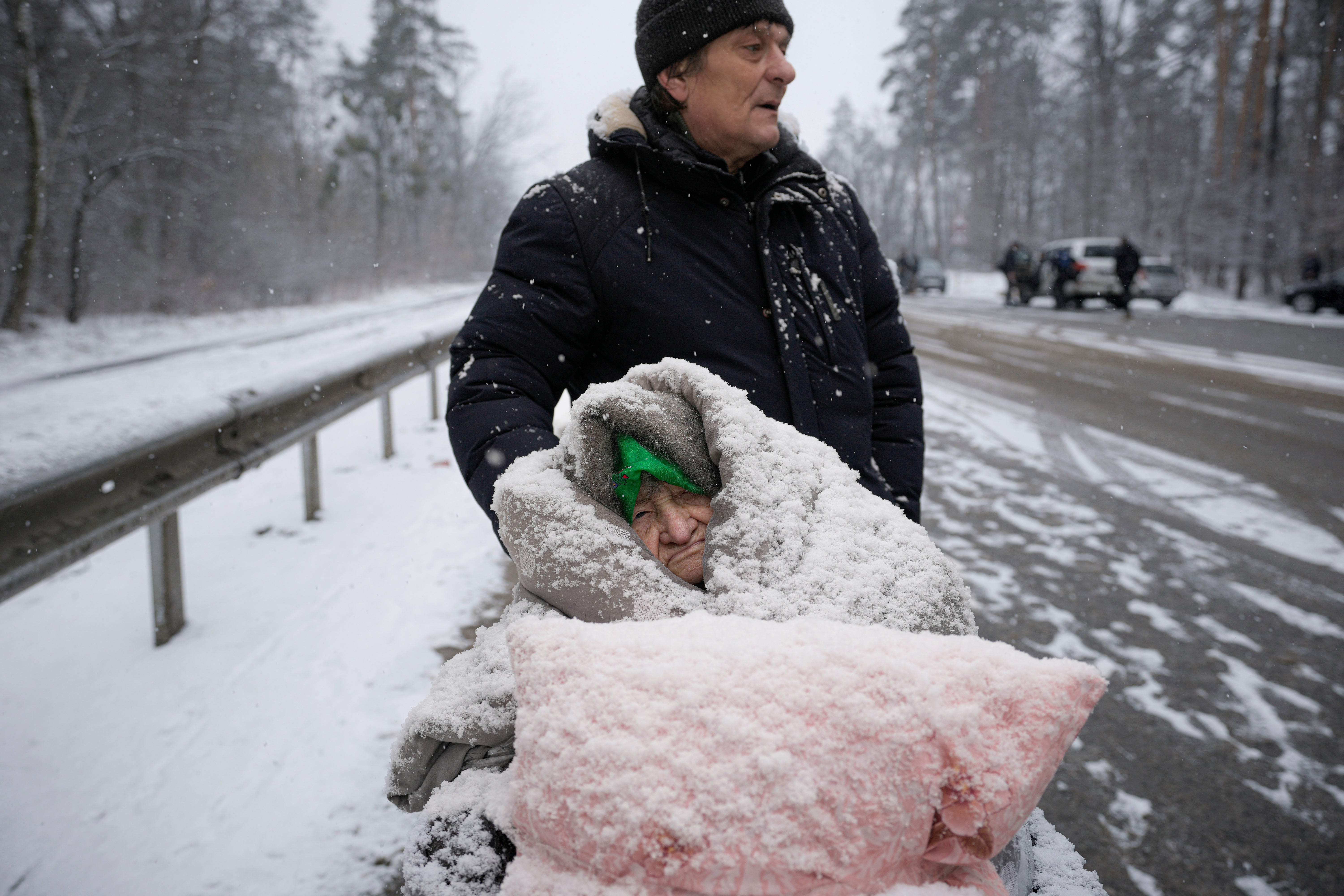 An elderly woman is coated in snow as she sits in a wheelchair after being evacuated from Irpin, on the outskirts of Kyiv, Ukraine