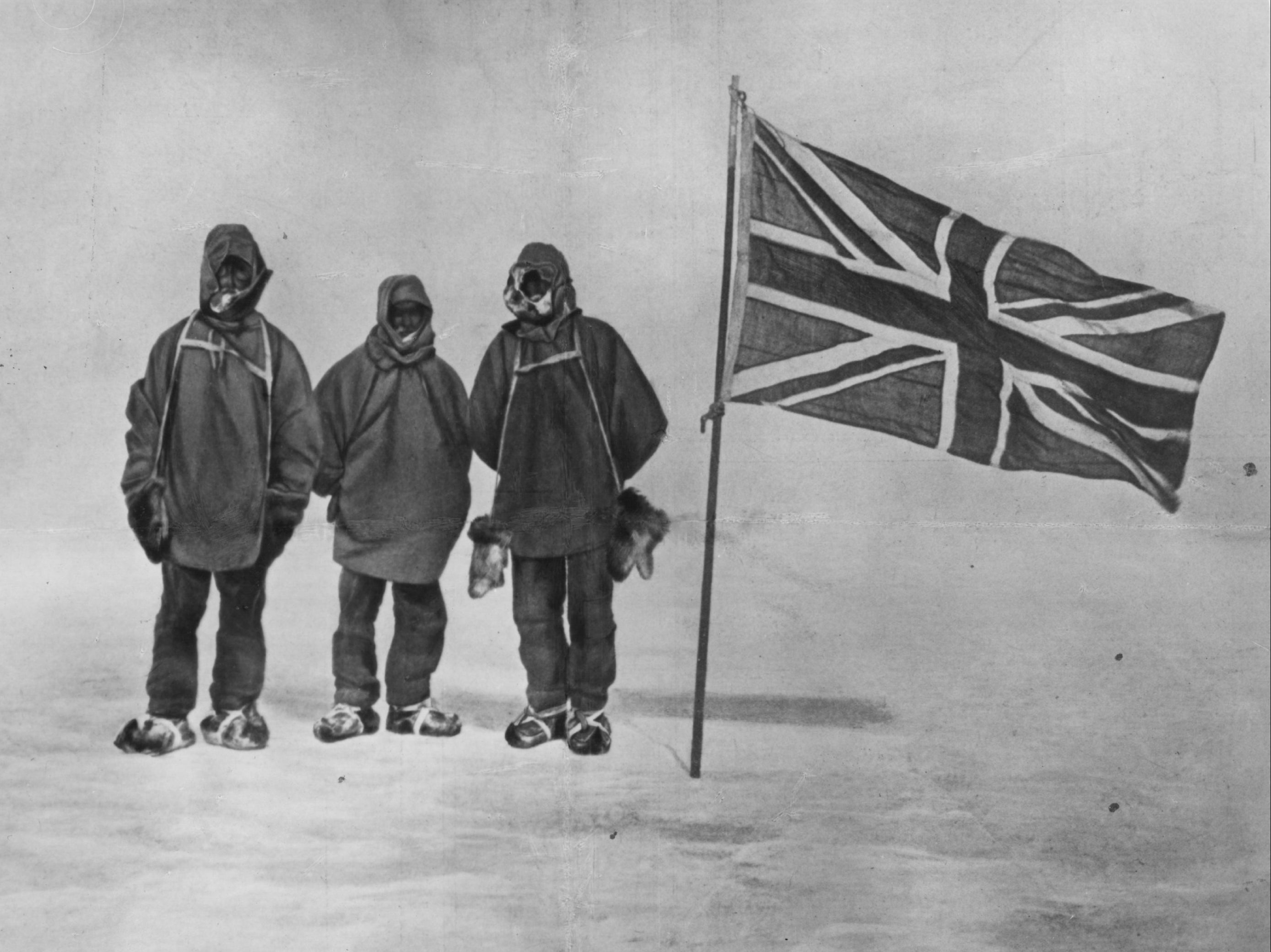 Sir Ernest Shackleto and two members of his expedition team beside a Union Jack within 111 miles of the South Pole