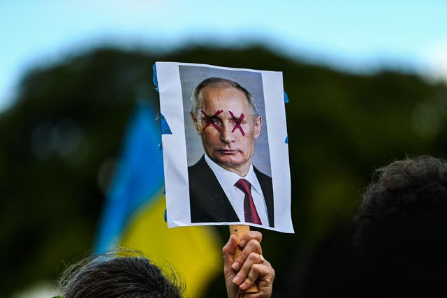 <p>A demonstrator holds a sign depicting Russian President Vladimir Putin during a rally in support of Ukraine in Miami, Florida</p>
