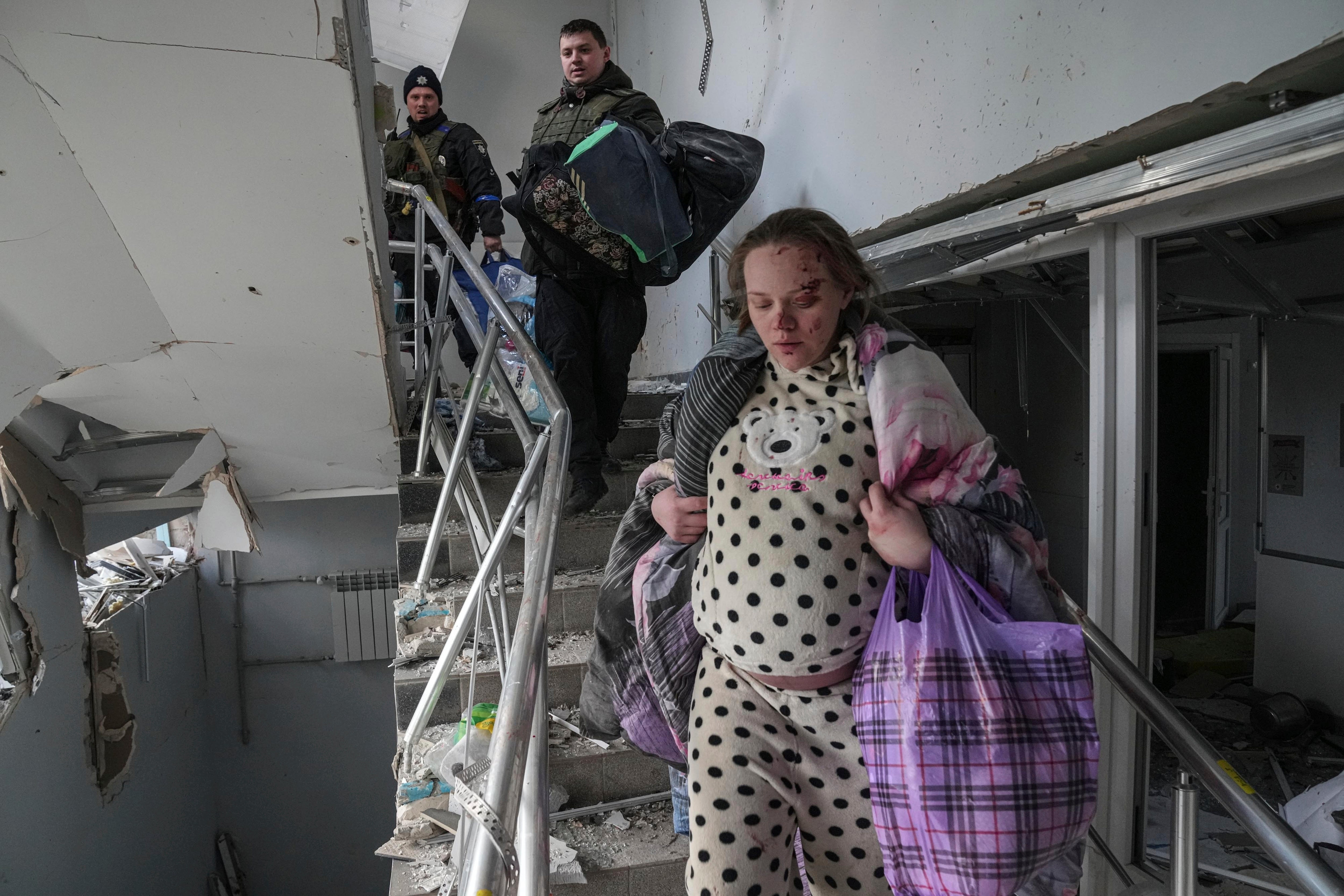 An injured pregnant woman walks downstairs in the damaged by shelling maternity hospital in Mariupol, Ukraine, 9 March 2022