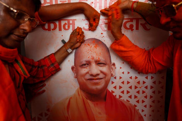 <p>BJP workers put coloured powder on a photograph of Adityanath as they celebrate the Uttar Pradesh election results in Lucknow on Thursday</p>