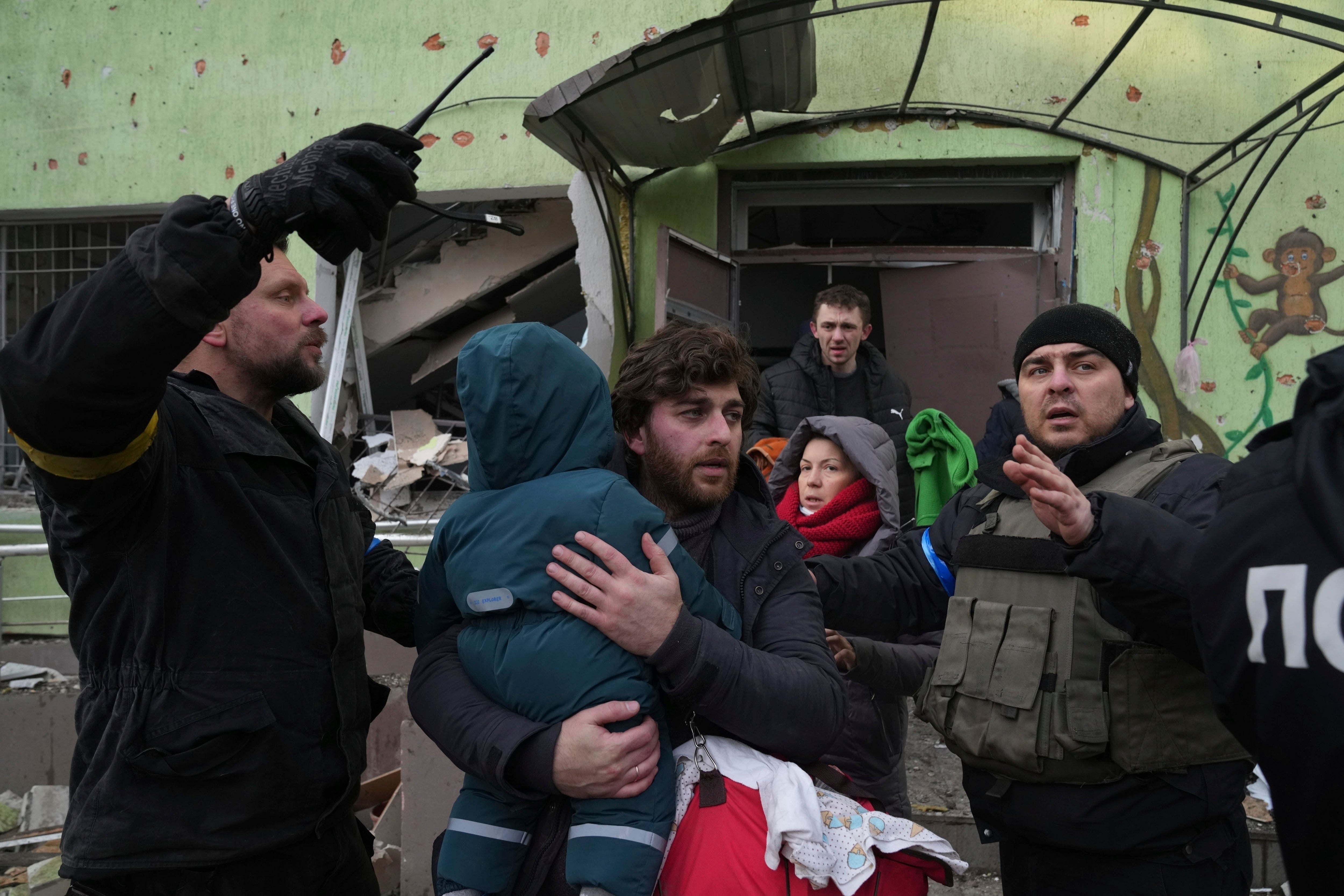 A man carries his child away from the ruined building.