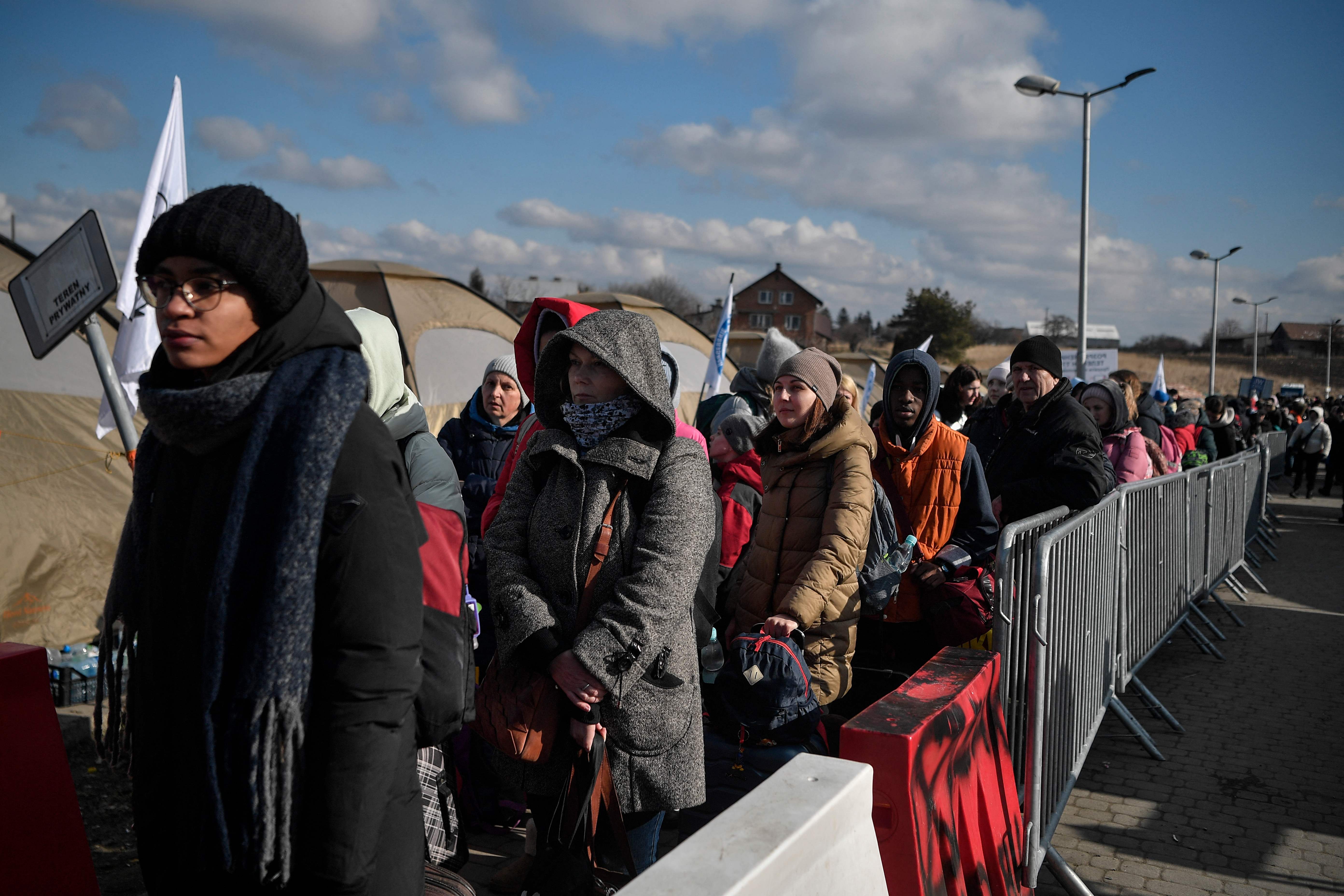 Ukrainians wait to border buses after crossing the border into Poland