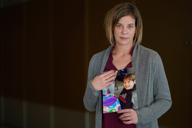 <p>Kara Trainor poses for a picture with a photo of her son, Riley, 11, after making a statement during a hearing in New York, Thursday, March 10, 2022</p>