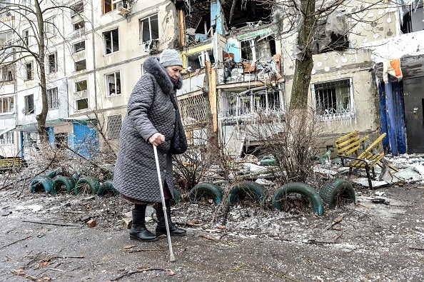 A woman walks by apartment building damaged after shelling the day before in Ukraine's second-biggest city of Kharkiv.