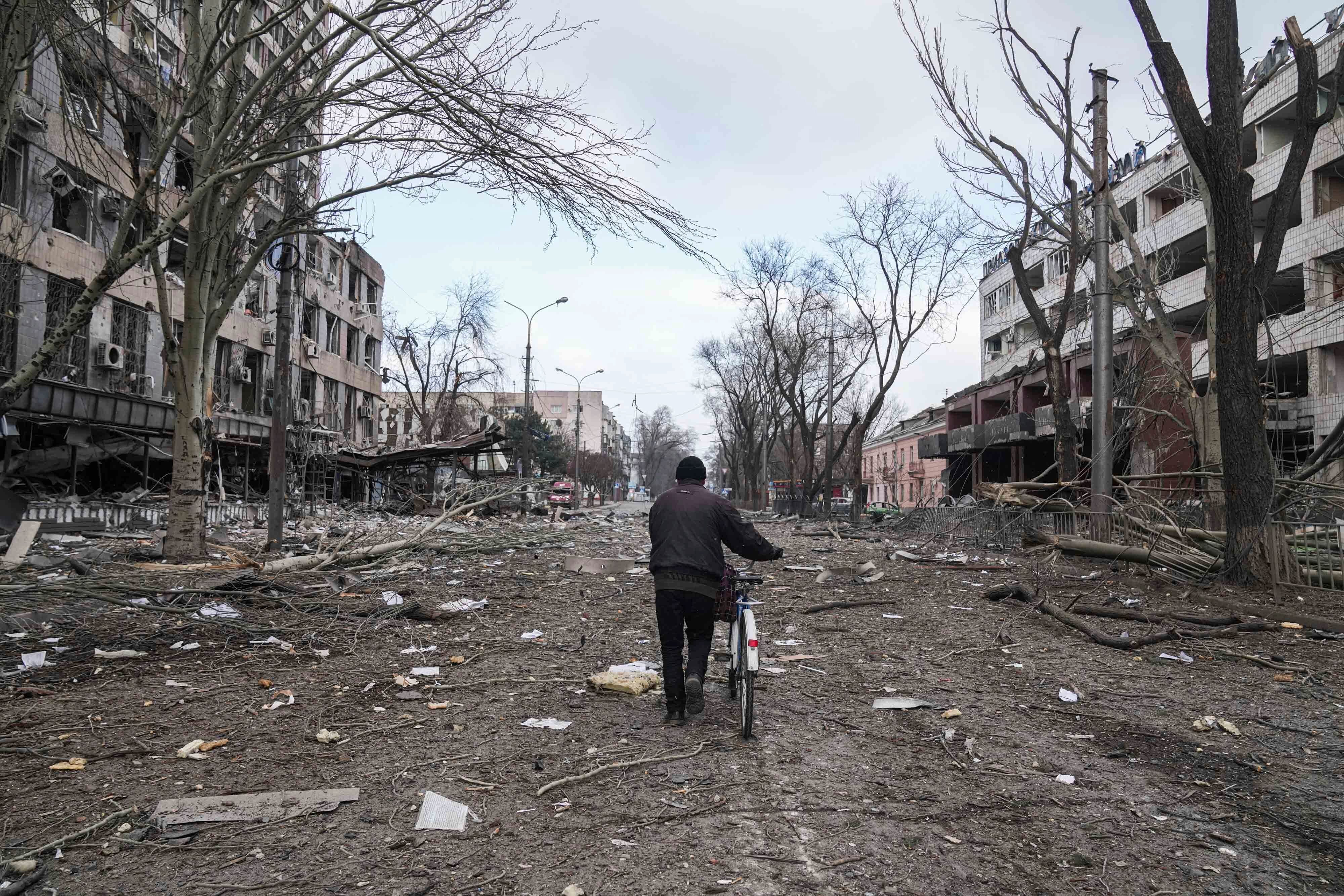 A man walks with a bicycle in a street damaged by shelling in Mariupol, Ukraine, on Thursday