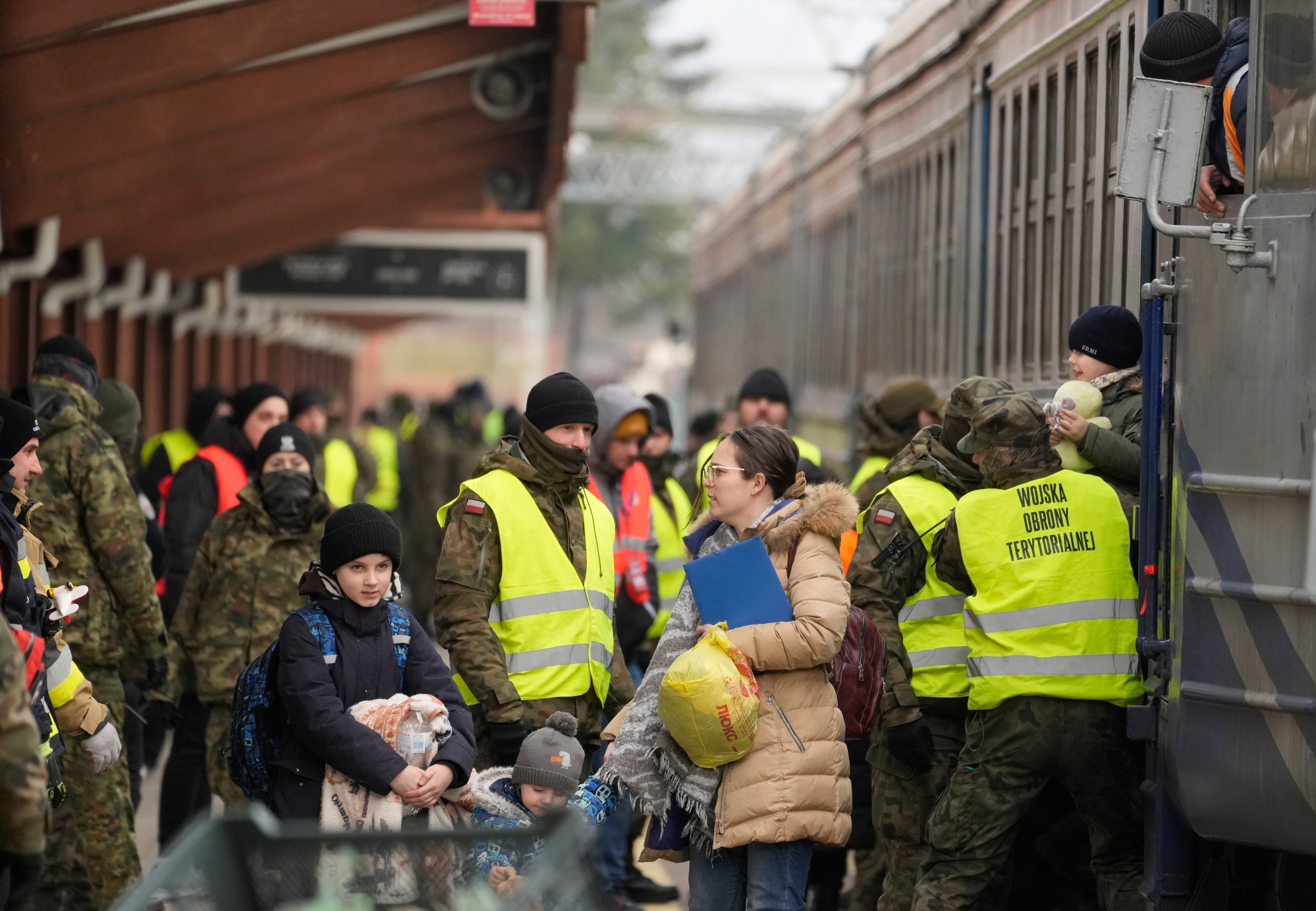 Soldiers help people arriving in Poland from Lviv (Czarek Sokolowski/AP)