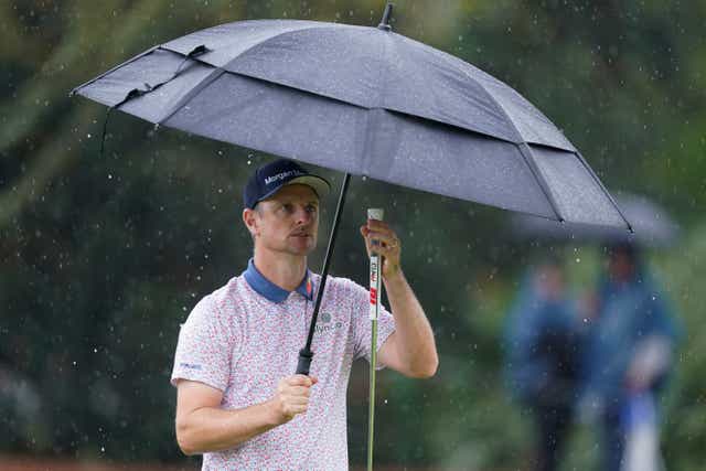 Justin Rose tries to stay dry during the delayed first round of the Players Championship (Gerald Herbert/AP)