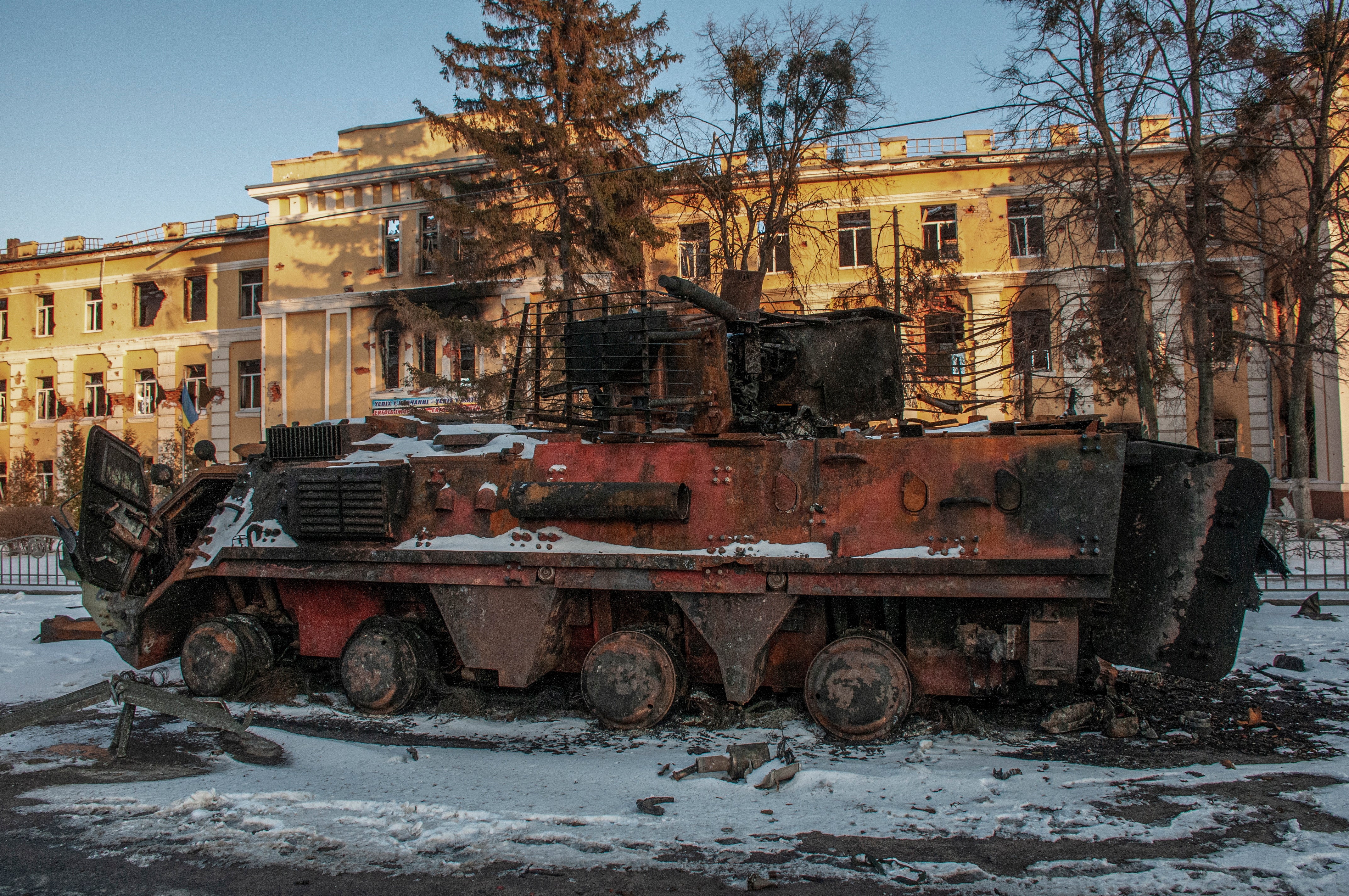 A destroyed armoured troop-carrier stands in front of the destroyed building in Kharkiv