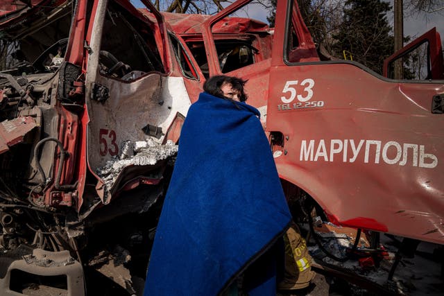 <p>Una mujer se cubre con una manta cerca de un camión destruido luego de los bombardeos a Mariúpol </p>