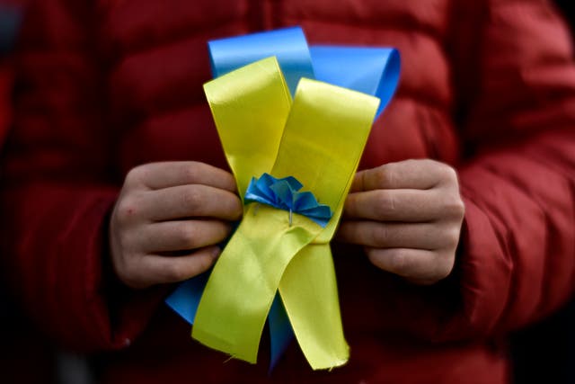 A Ukrainian woman holds a bow in the colours of the Ukraine flag while taking part in a protest in Pamplona, northern Spain (Alvaro Barrientos/AP)
