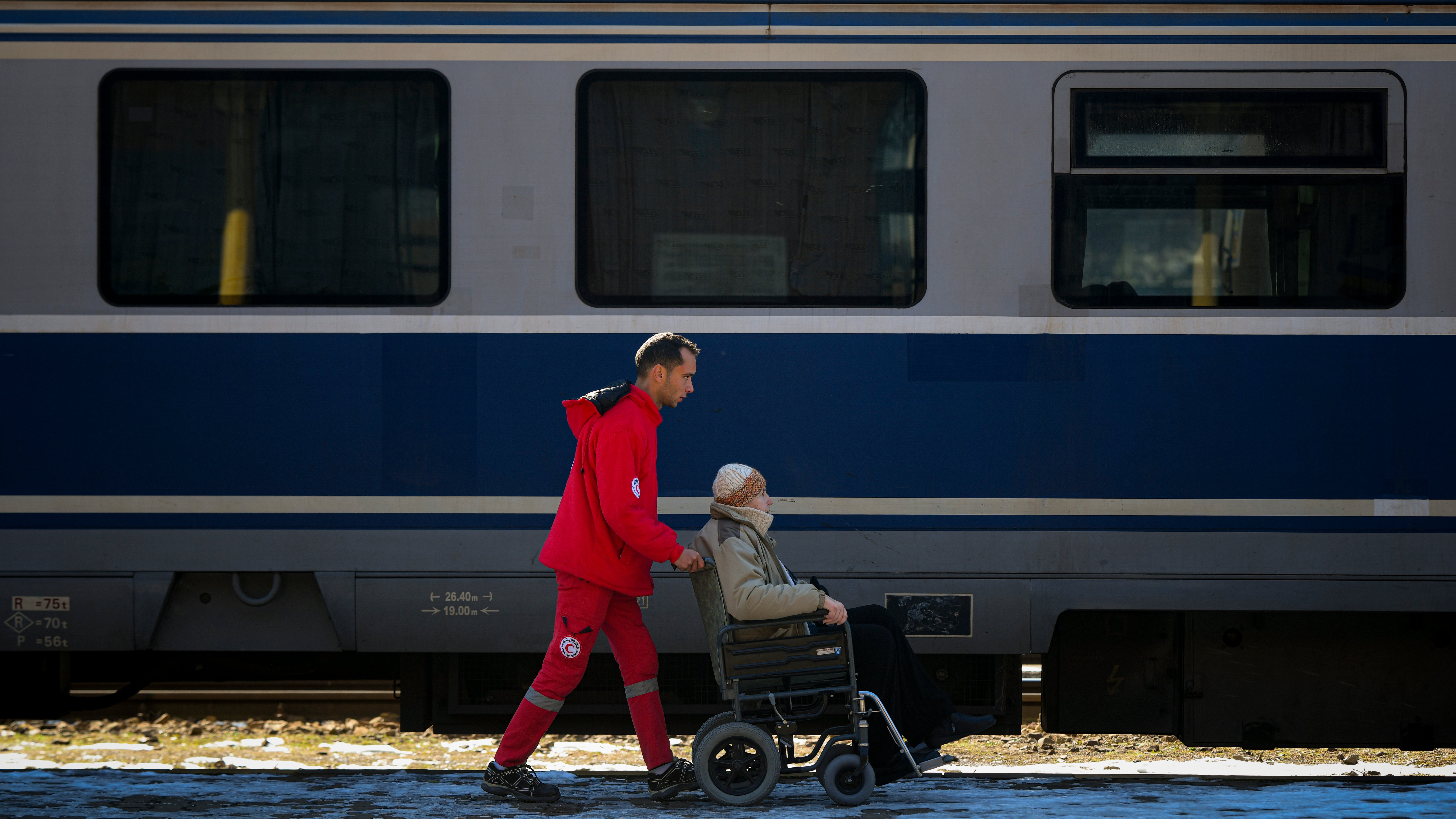 A volunteer helps transport a refugee fleeing the war from Ukraine (Andreea Alexandru/AP)