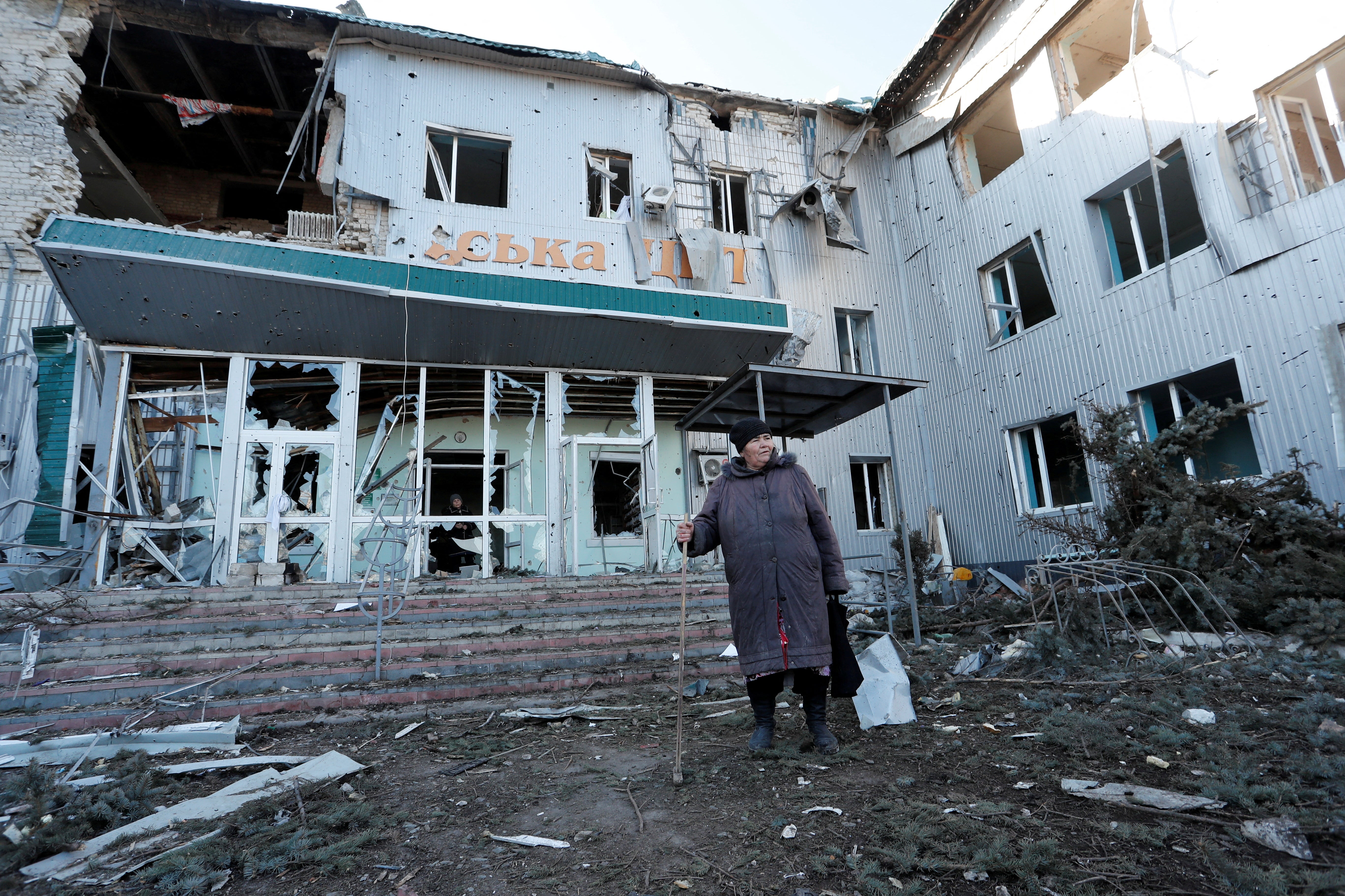 A woman stands outside a local hospital, which was destroyed during Ukraine-Russia conflict in the separatist-controlled town of Volnovakha in the Donetsk region