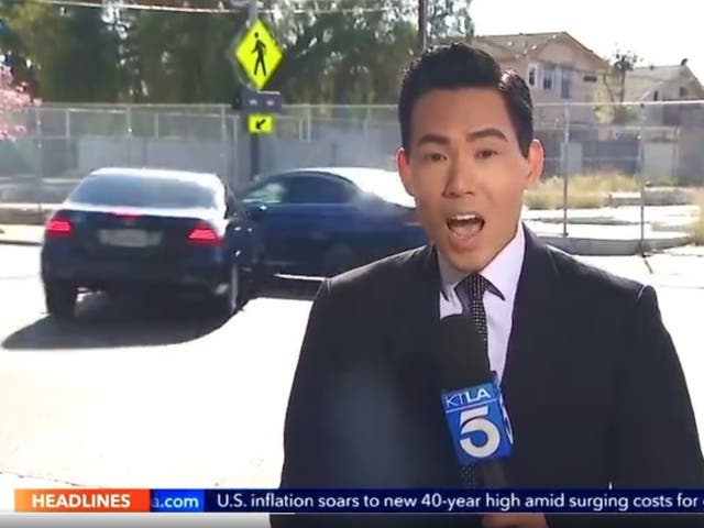 El reportero de KTLA, Gene Kang, habla mientras los autos chocan detrás de él.