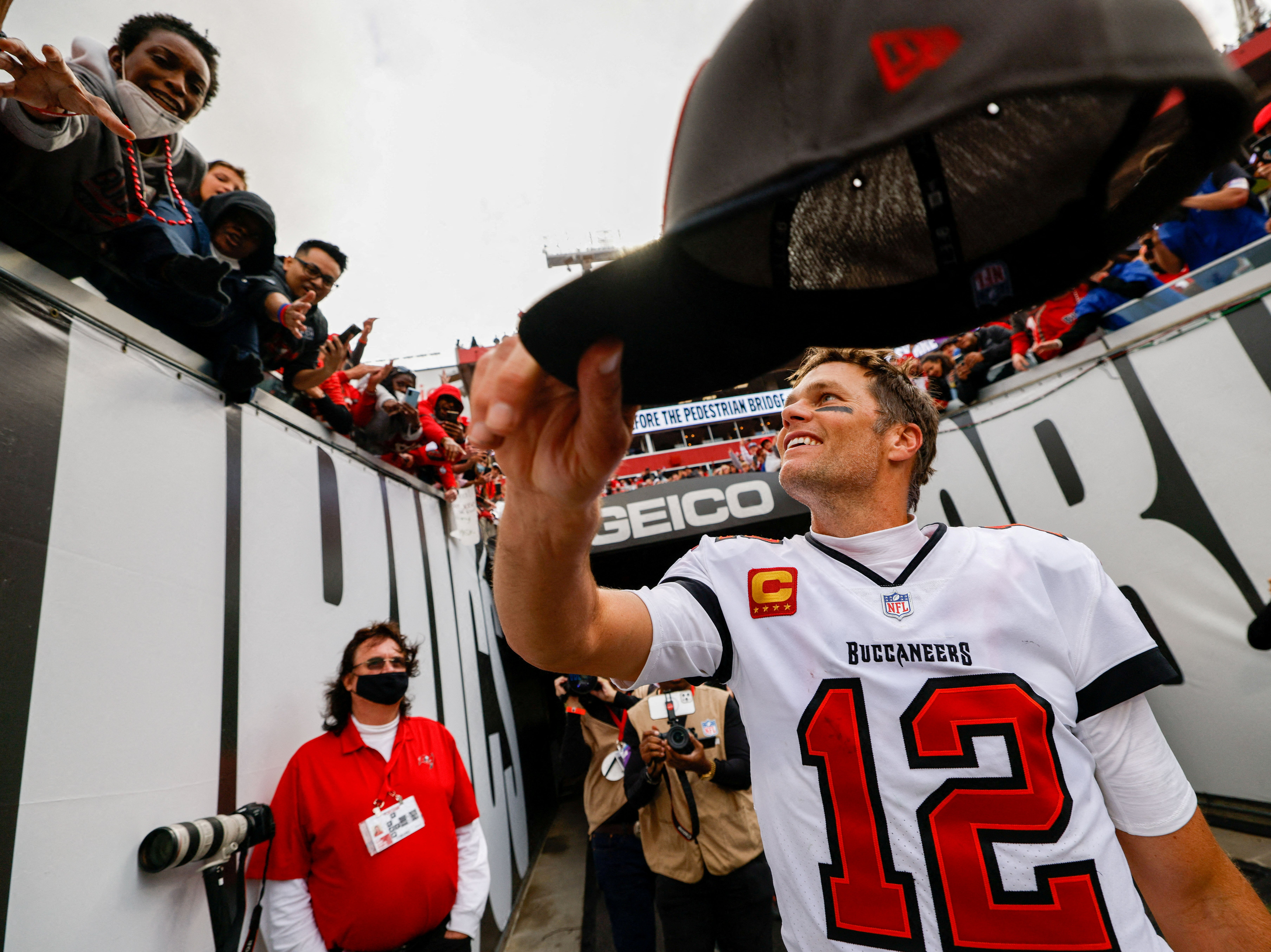 Tom Brady hands fans his hat after beating the Philadelphia Eagles in January 2022