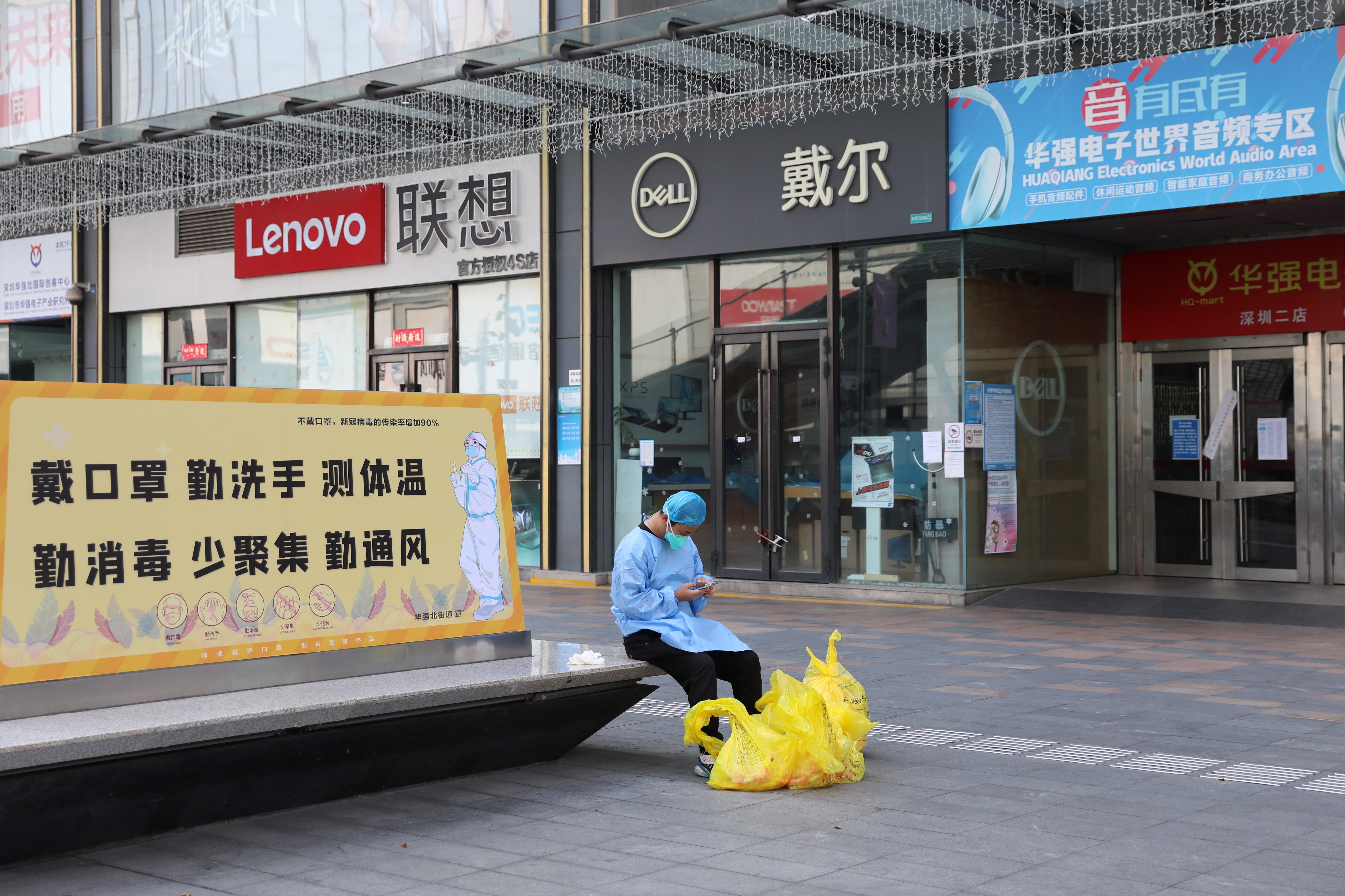 A man checks his phone outside closed shops in Huaqiangbei