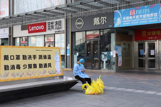 <p>A man checks his phone outside closed shops in Huaqiangbei </p>