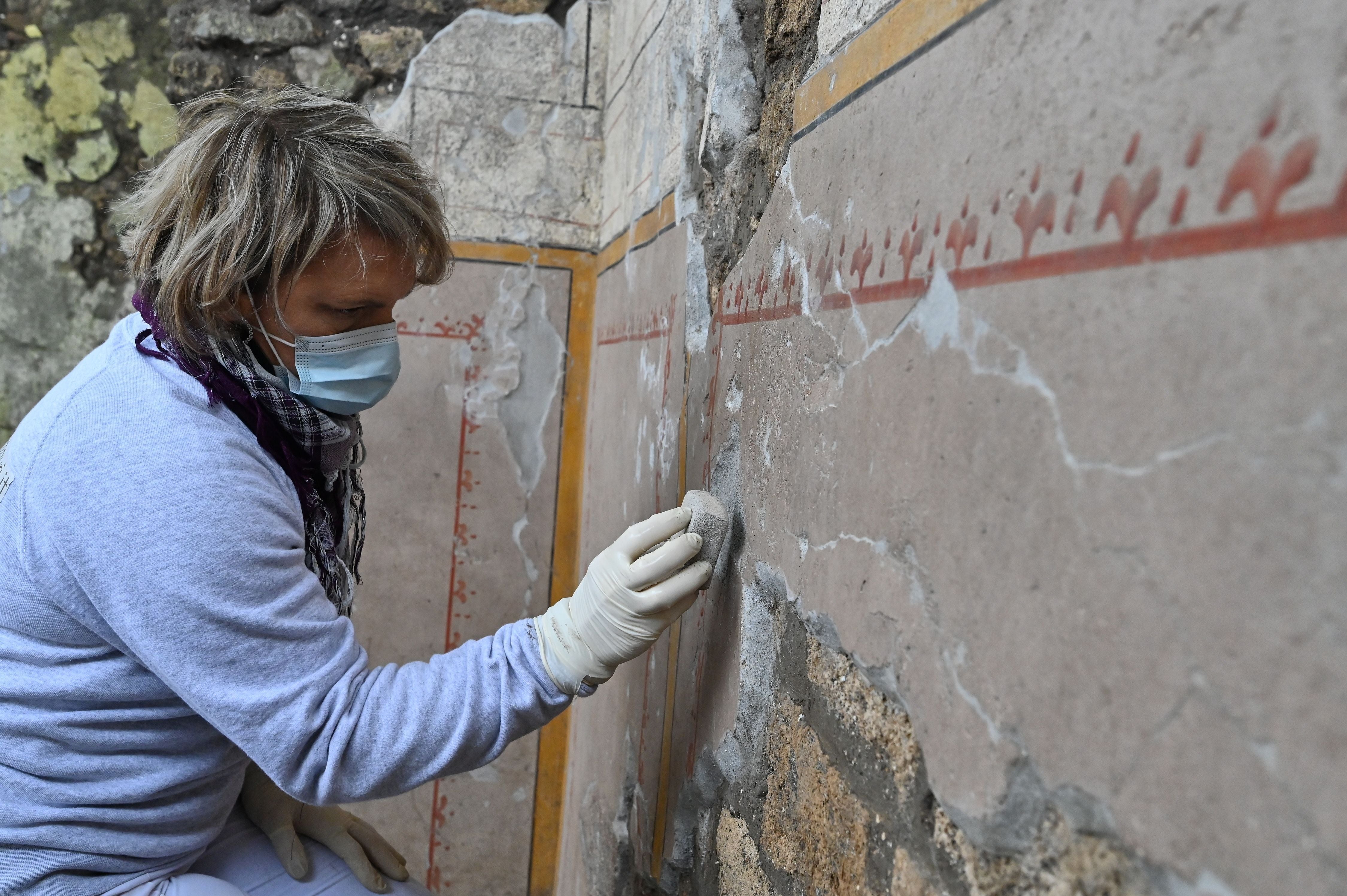 A restorer works on the newly discovered thermopolium on the Pompeii site