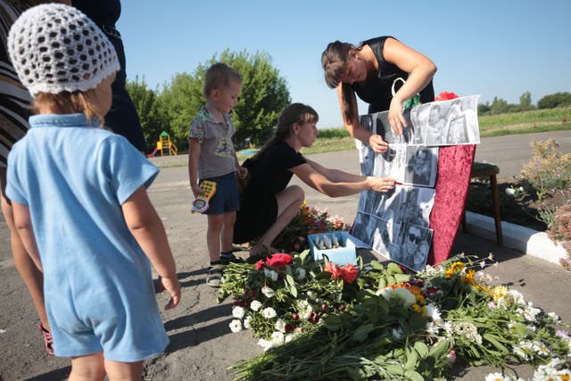 <p>Local villagers place pictures of the passengers of MH17 flight at a makeshift memorial in Petropavlivka village, Donetsk region, on the second anniversary of the tragedy on 17 July 2016</p>