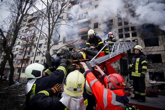 Los bomberos evacuan a un hombre de un edificio de apartamentos afectado por bombardeos en Kiev