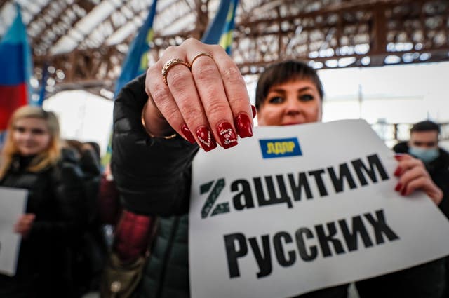 <p>A Russian woman holds poster ‘Let’s protect the Russians’ and shows the letters V and Z on her nails during a demonstration supporting Russian troops in Moscow</p>