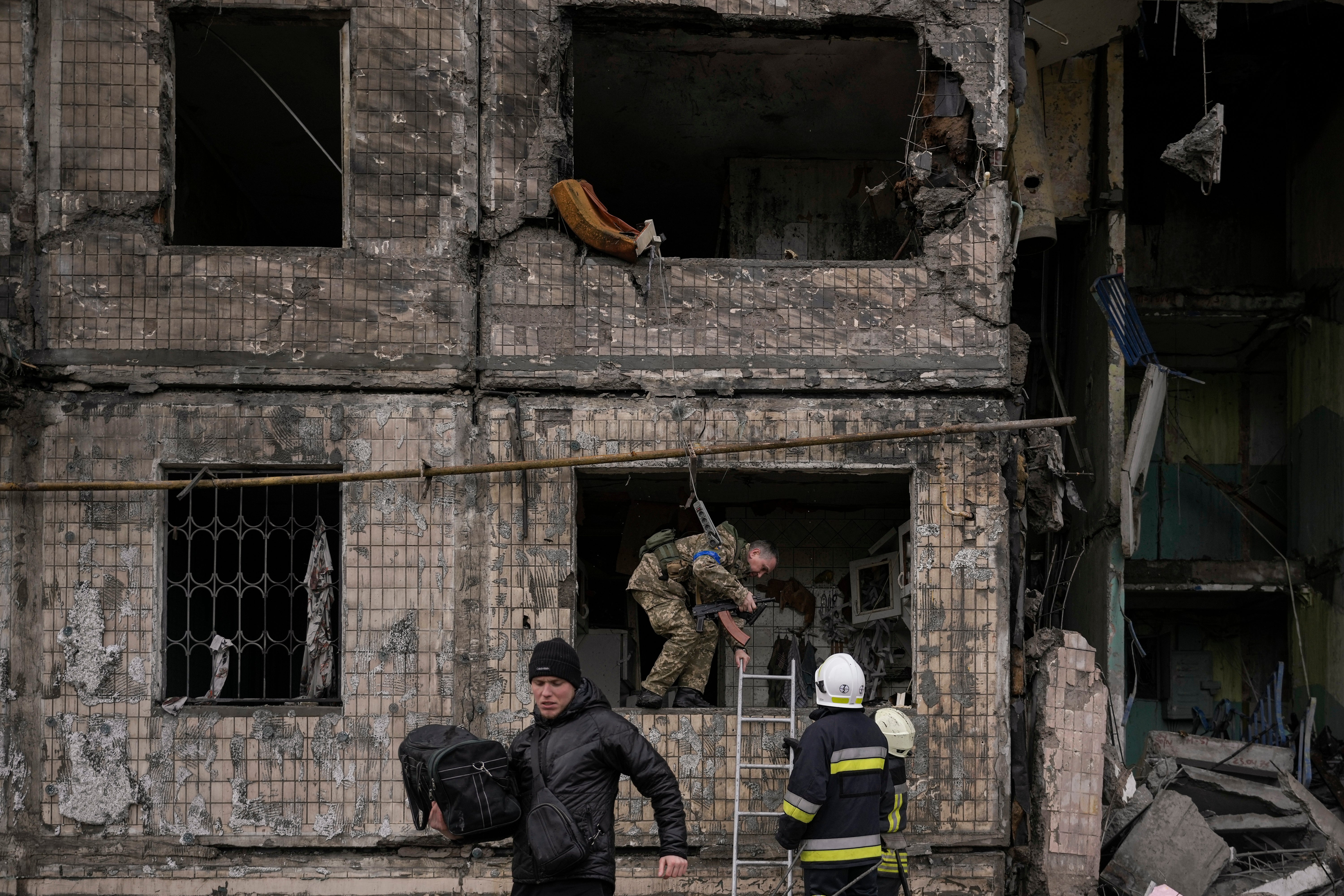 People retrieve belongings from an apartment in a block which was destroyed by an artillery strike in Kyiv, Ukraine on Monday, 14 March