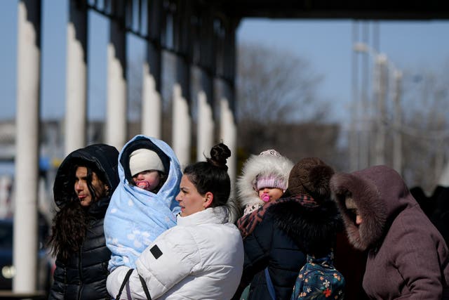 Refugees fleeing the war from neighbouring Ukraine hold their babies at the Romanian-Ukrainian border (Andreea Alexandru/AP)