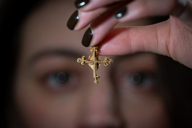 A 12th century cross, which sold at auction for £12,400, is held by a Dix Noonan Webb employee ahead of the auction (Aaron Chown/ PA)