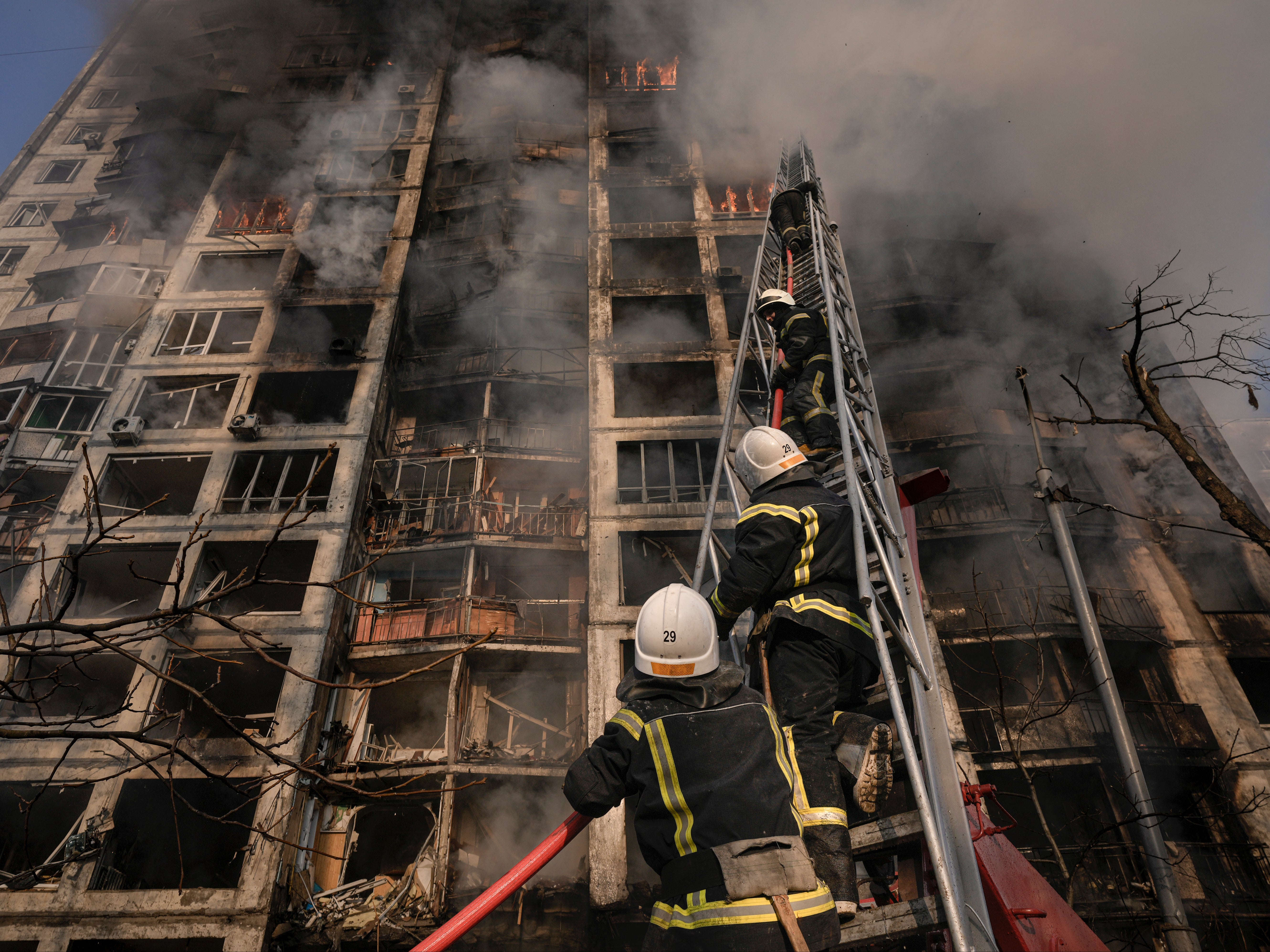 Firefighters climb a ladder while working to extinguish a blaze in a destroyed apartment building after a bombing in a residential area in Kyiv