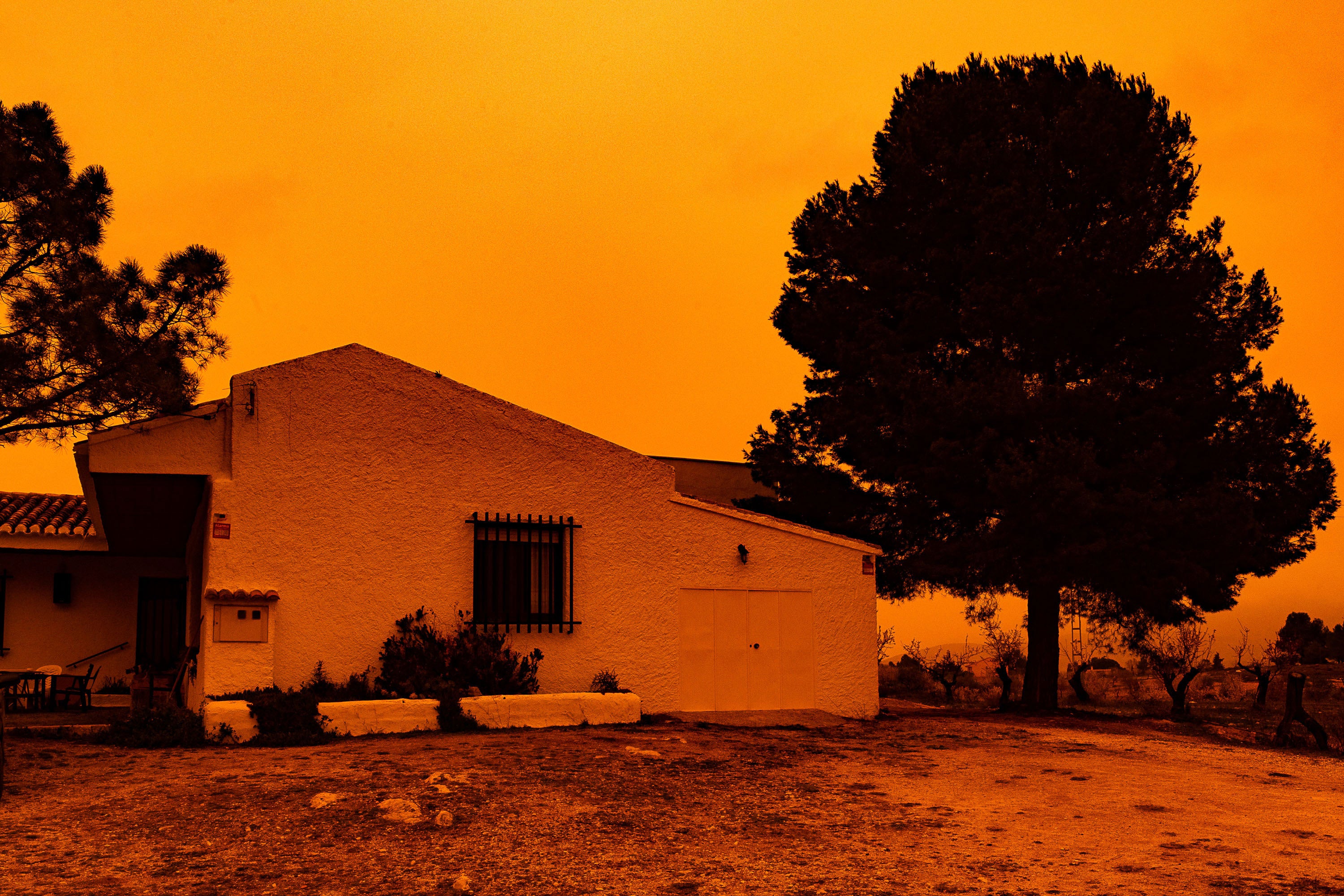 <p>An orange sky is seen over a building in Navares, southeastern Spain on 14 March. A mass of hot air from the Sahara dumped vast amounts of dust after crossing the Mediterranean</p>