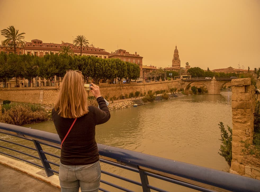 На этой неделе женщина фотографирует центр города Мурсия, Испания, покрытый тяжелой пылью