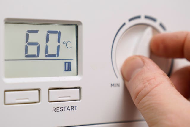 A homeowner turns down the temperature of a gas boiler (Andrew Matthews/PA)