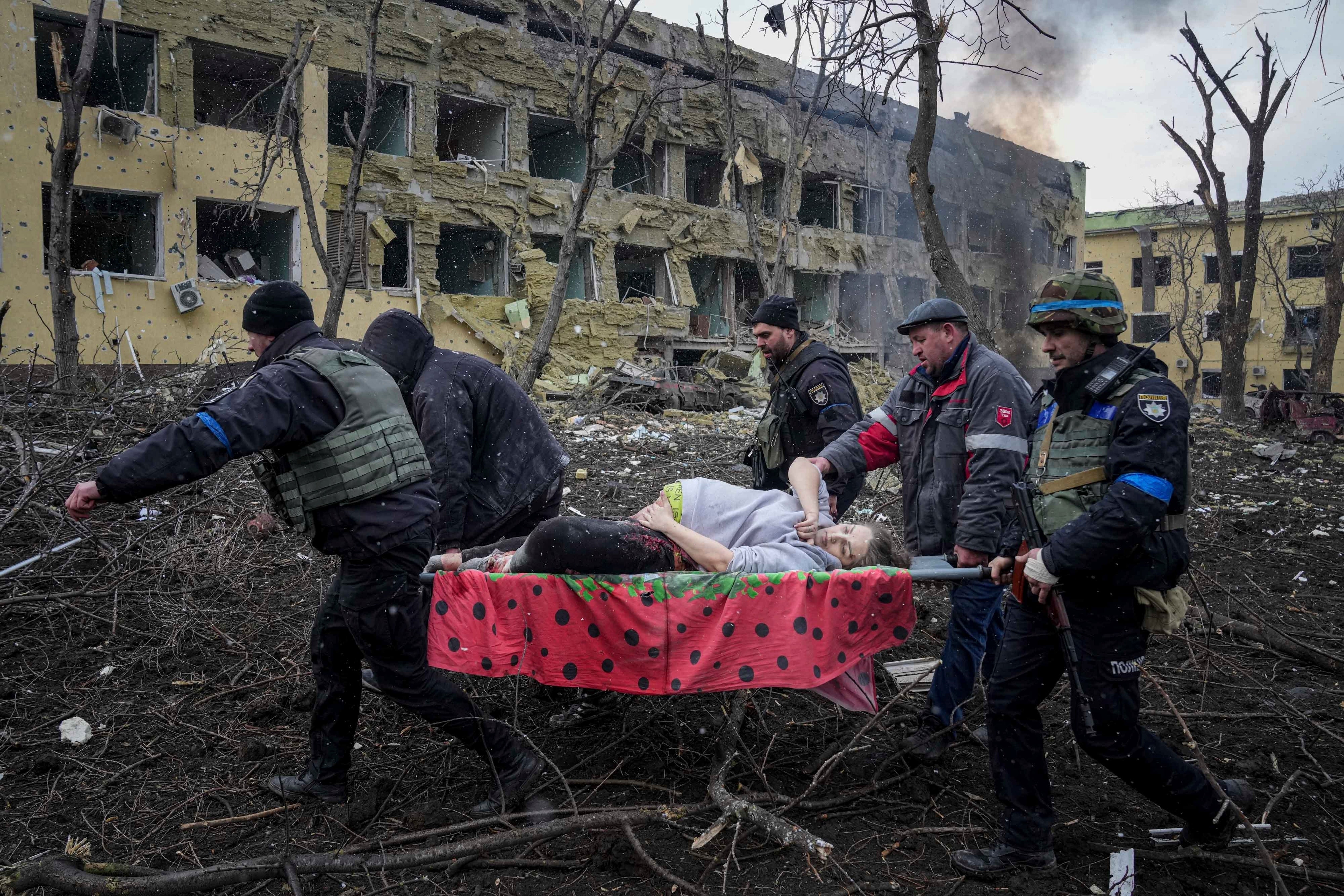 Ukrainian emergency workers and volunteers carry an injured pregnant woman from a maternity hospital damaged by shelling in Mariupol