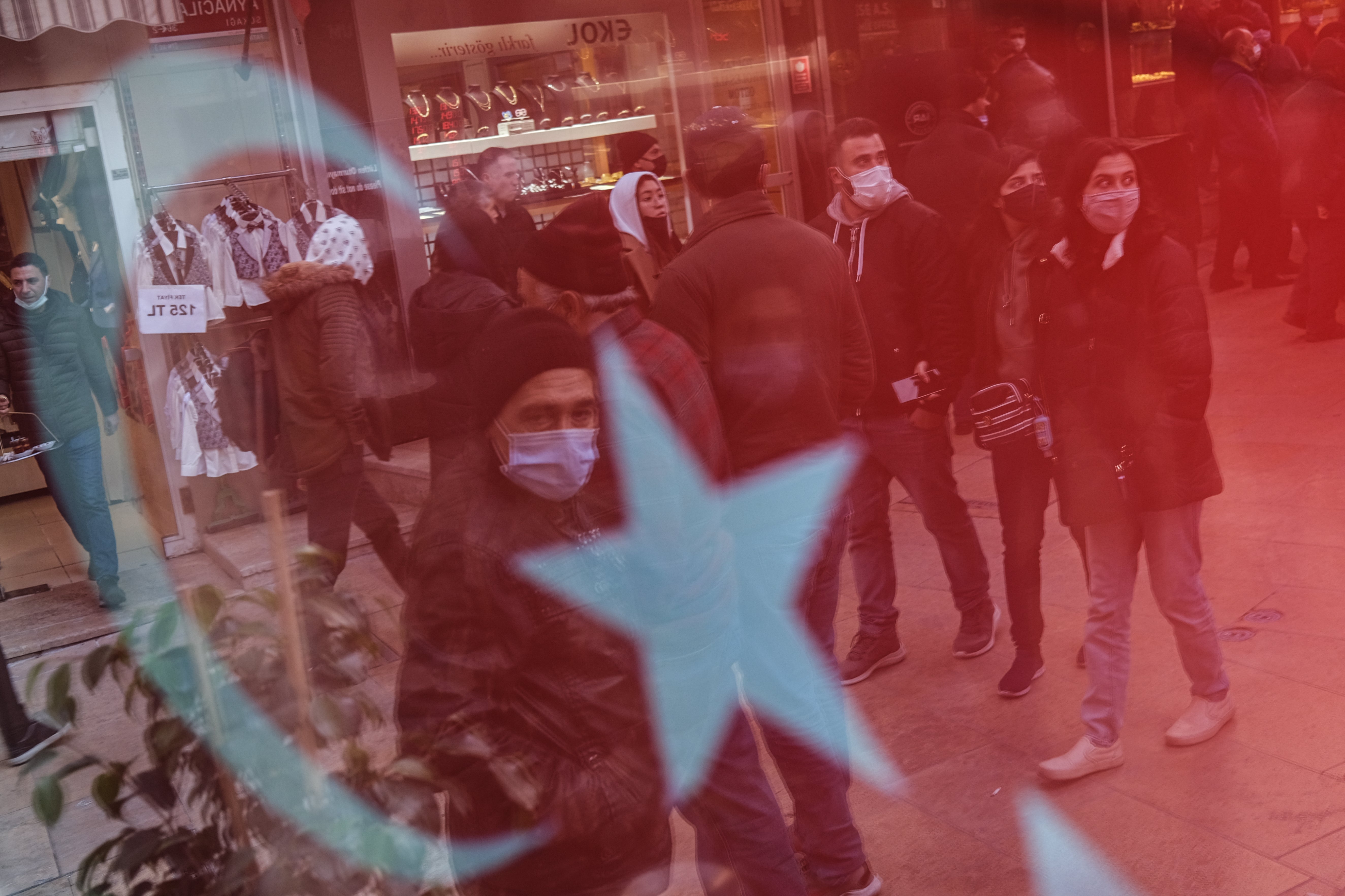 People are seen through a reflection of the Turkish flag as they do shopping at Grand Bazaar in Istanbul