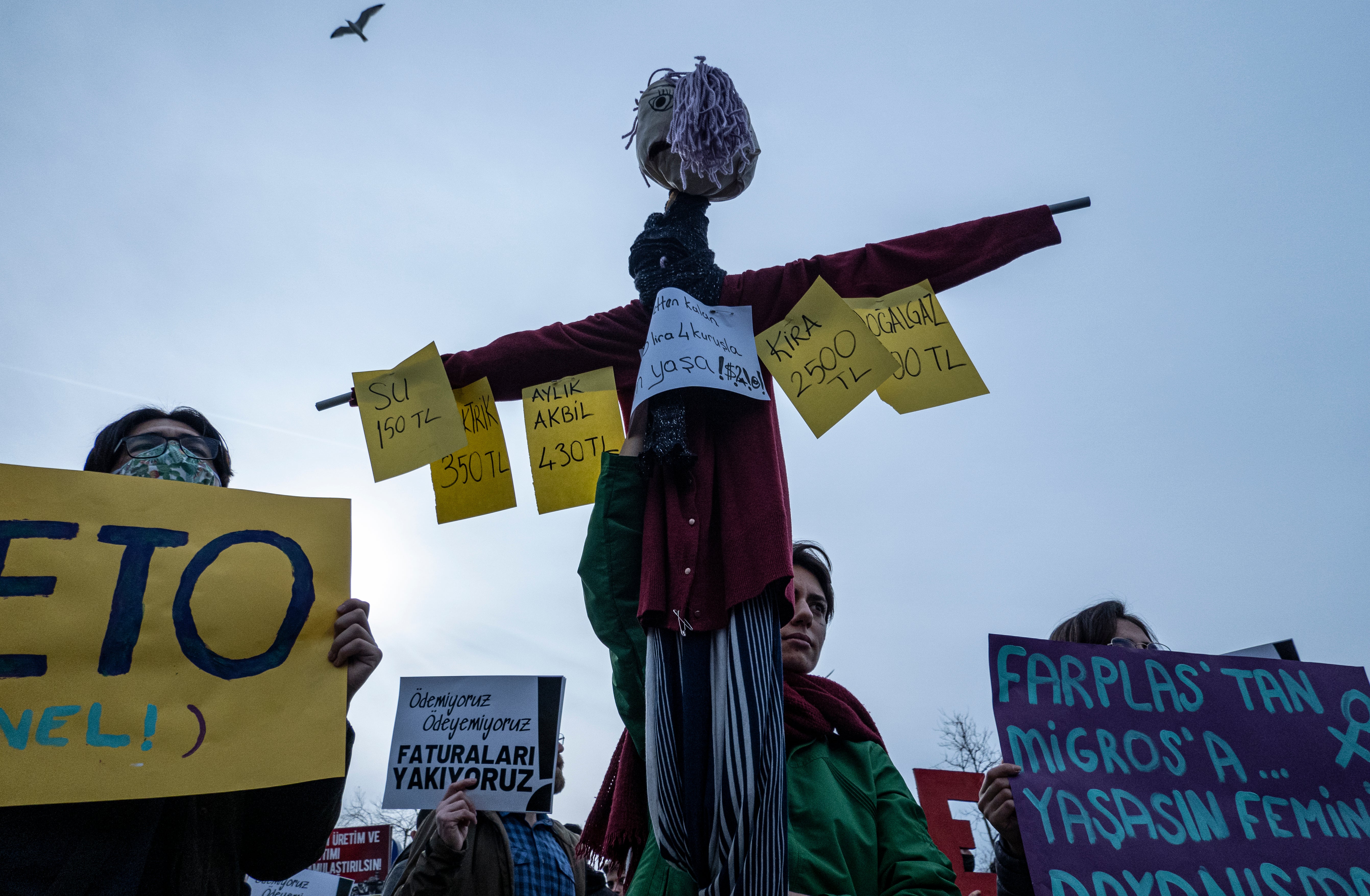 A protester holds a scarecrow showing the bills she has paid during a protest against price hikes in Istanbul