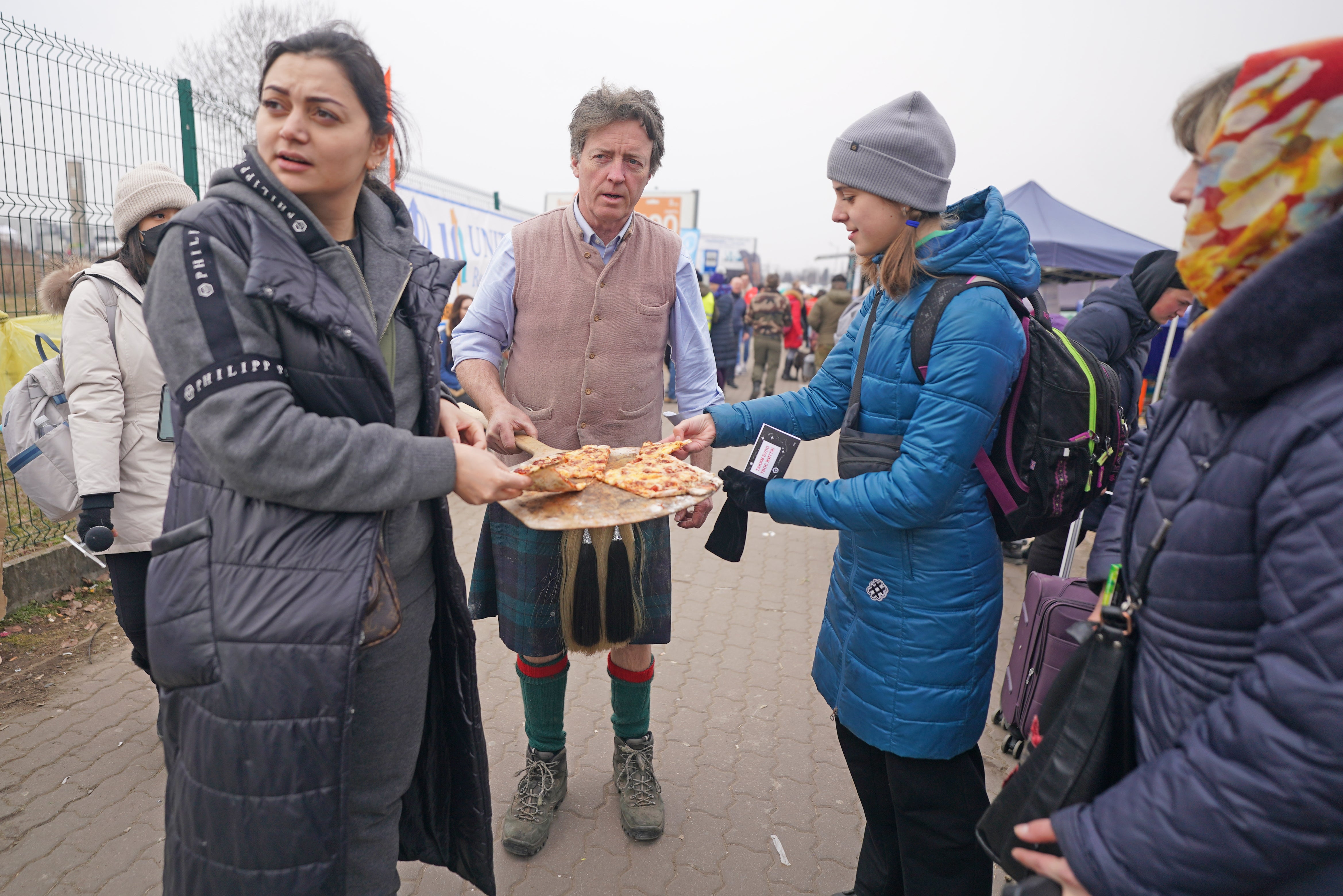 David Fox-Pitt hands out pizza to people crossing the border point from Ukraine into Medyka, Poland (Victoria Jones/PA)