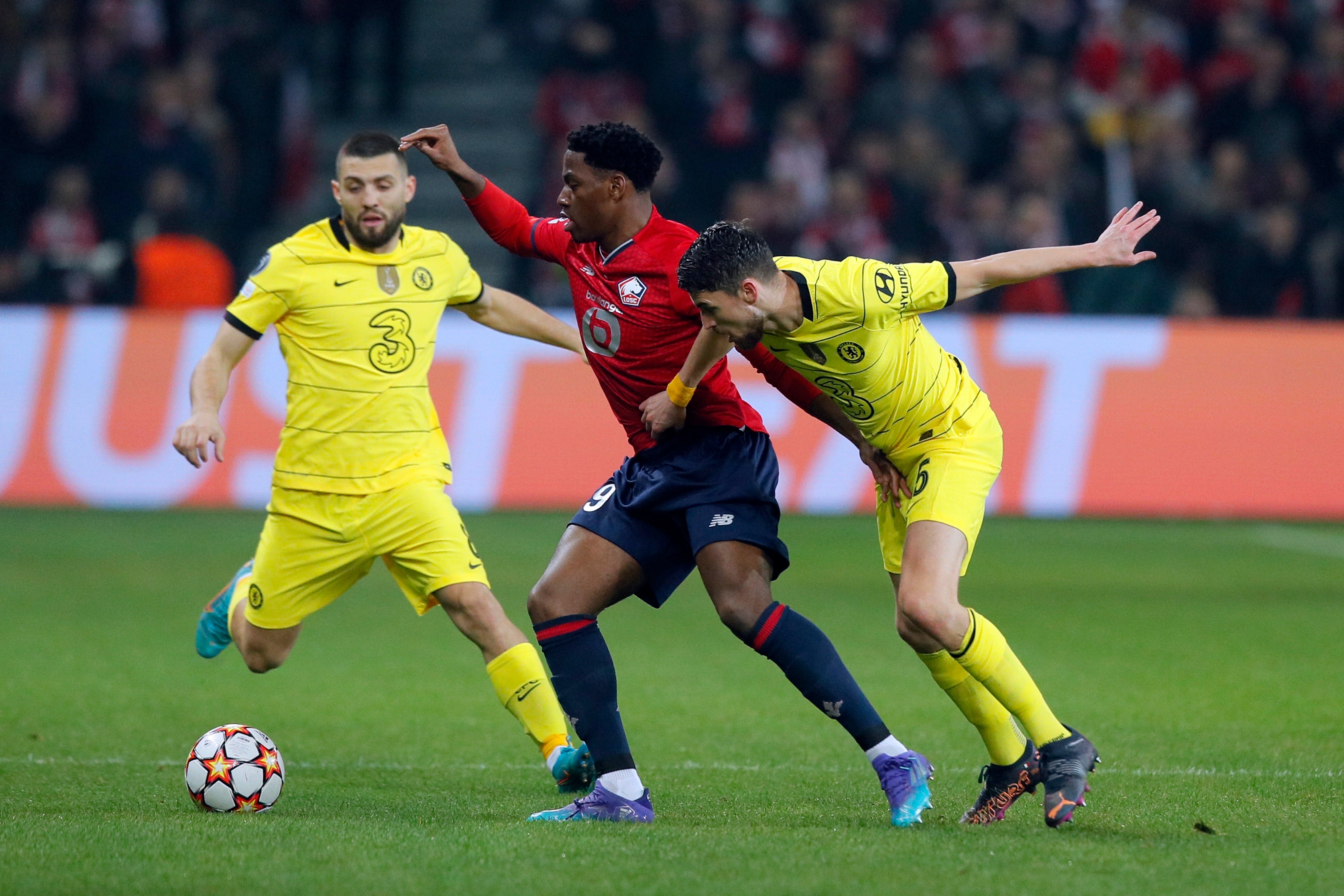 Lille’s Jonathan David, center, keeps the ball as Chelsea’s Jorginho, right, and Mateo Kovacic try to stop him during the Champions League second leg