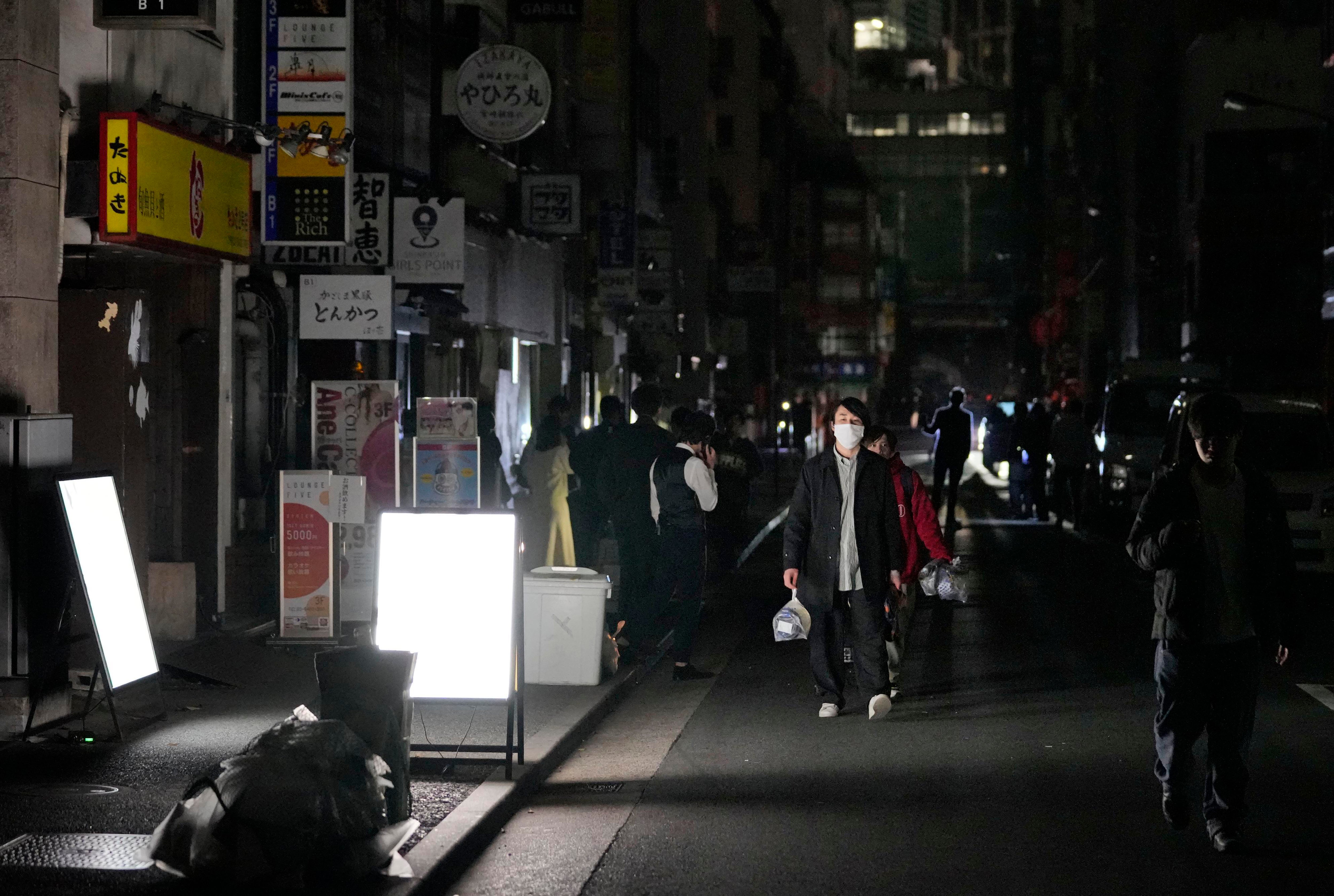 People walk on a street during a blackout in Tokyo on Thursday, following an earthquake