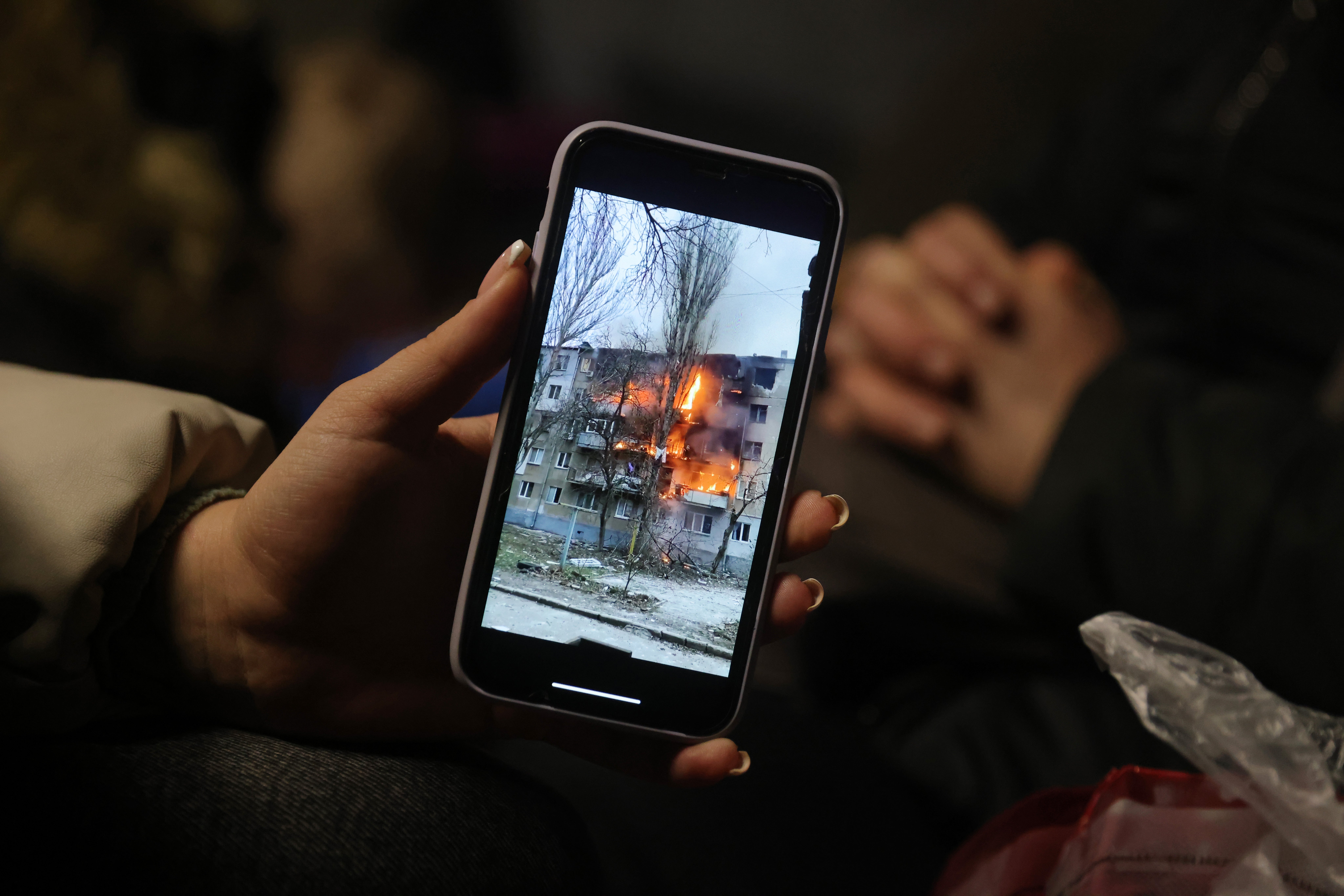 Iryna Holoshchapova, a Ukrainian refugee who fled the embattled city of Mykolaiv to Medyka in Poland, shows a video on her smartphone of an apartment block in Mykolaiv on fire following a Russian attack, 9 March 2022