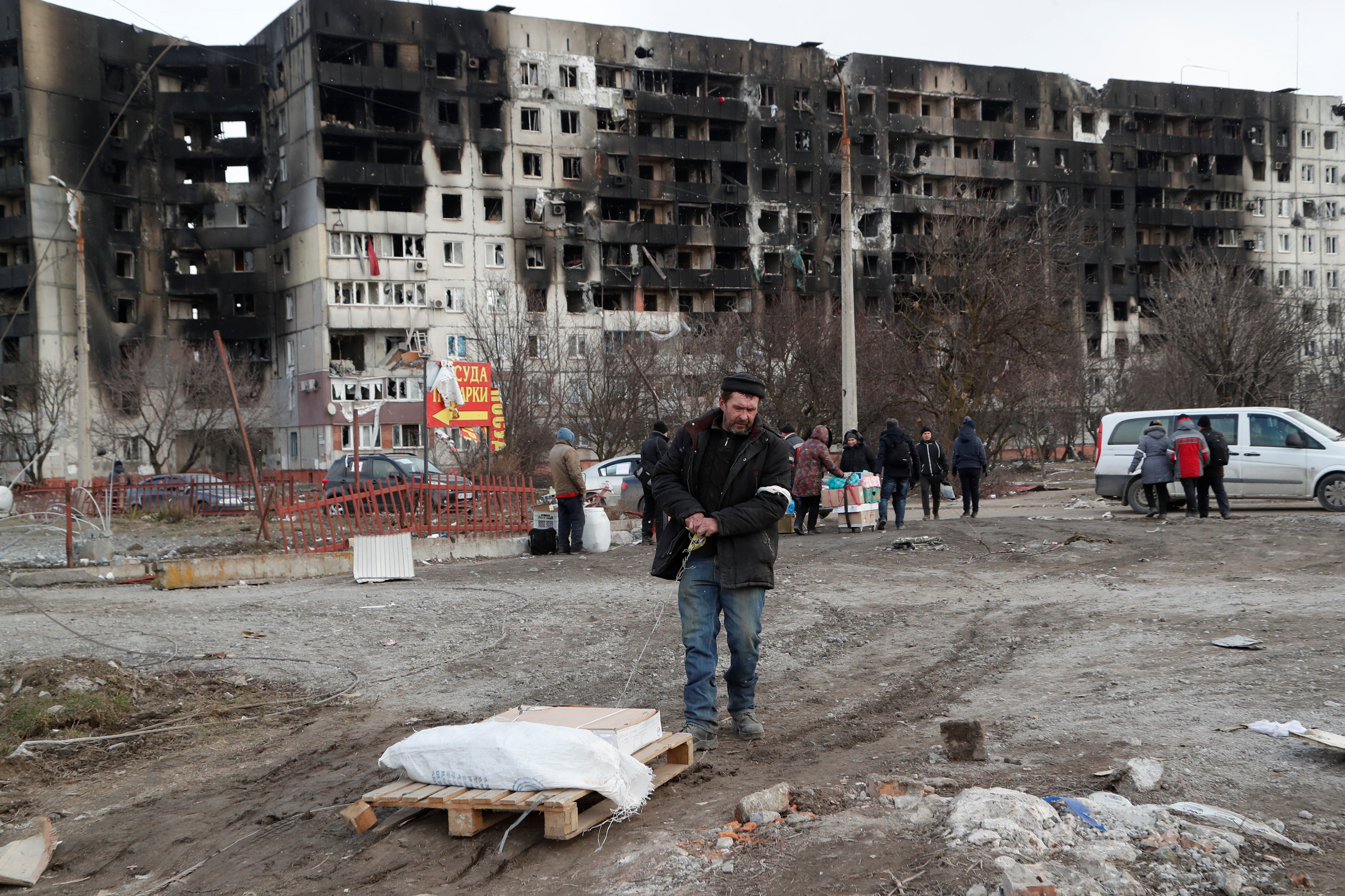 People gather near a block of flats, which was destroyed during Ukraine-Russia conflict in the besieged southern port city of Mariupol