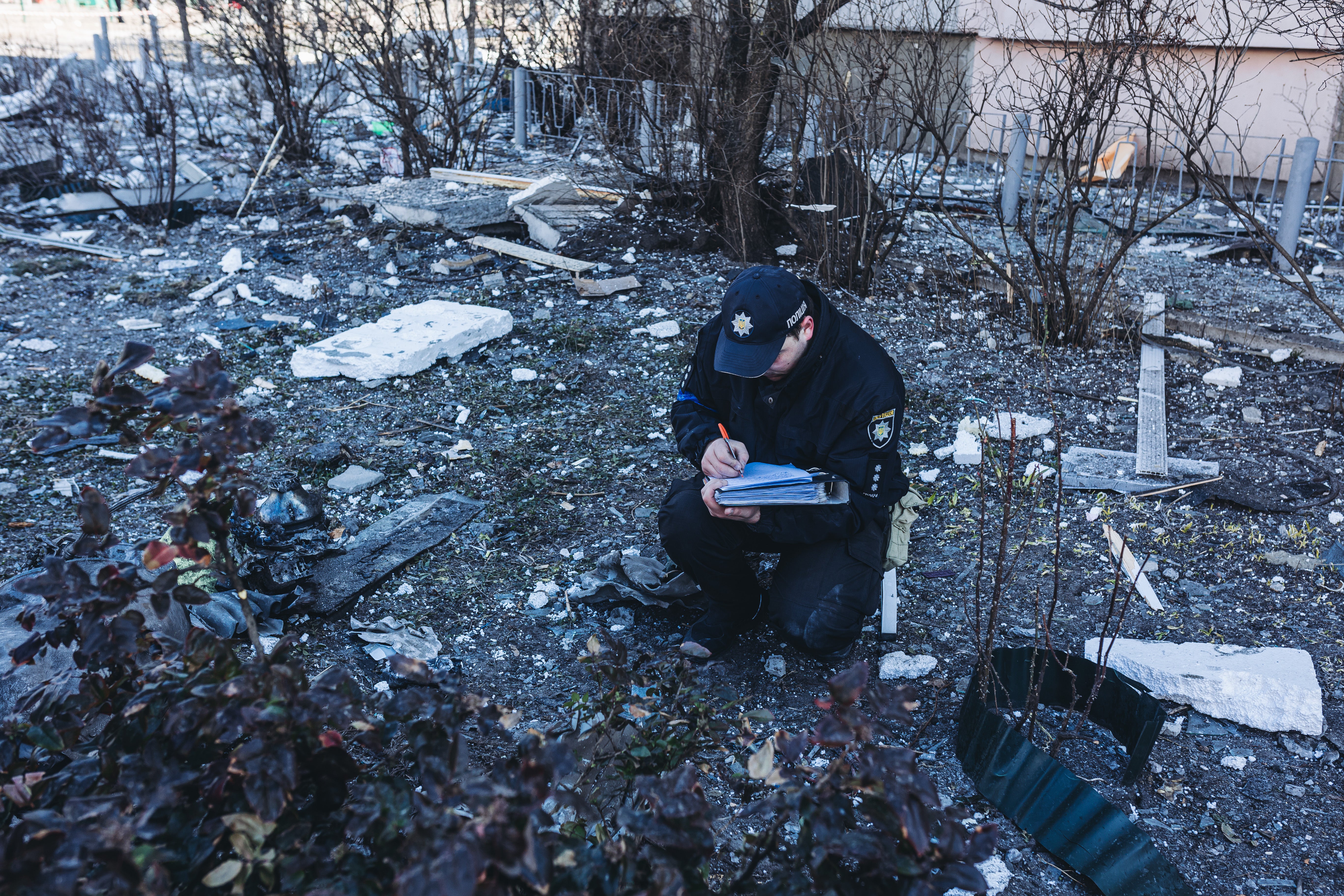 A policeman collects evidence of a falling shell in a house in Kyiv