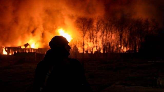 <p>A Ukrainian serviceman is backdropped by a blaze at a warehouse after a bombing on the outskirts of Kyiv, Ukraine</p>